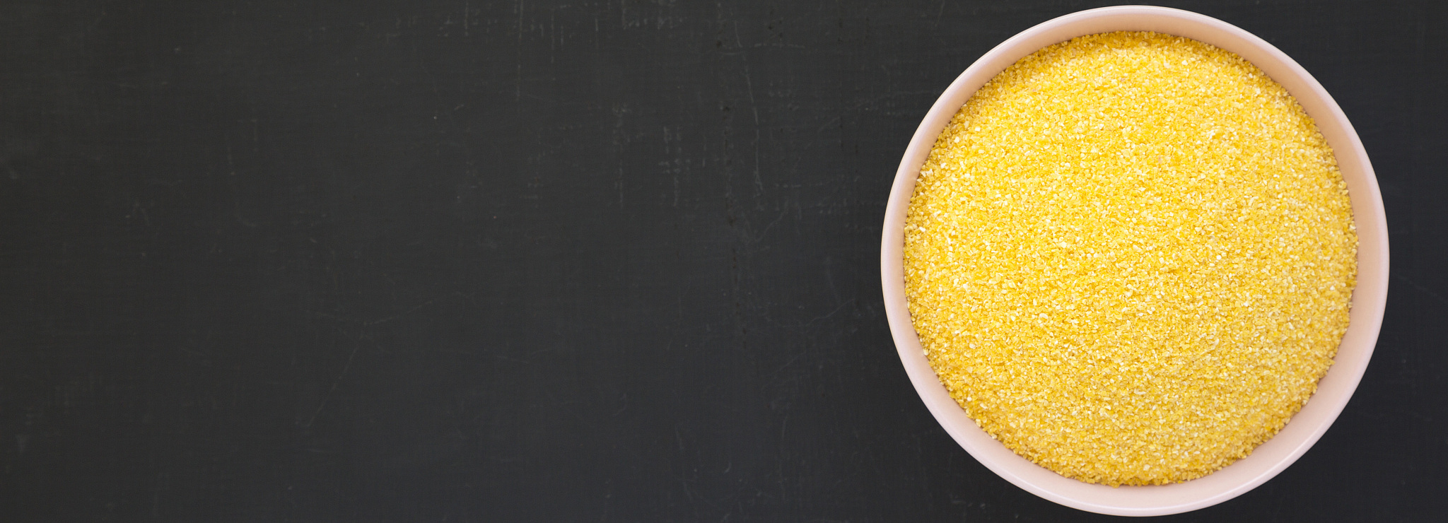 dry organic masarepa corn meal in a pink bowl over black surface