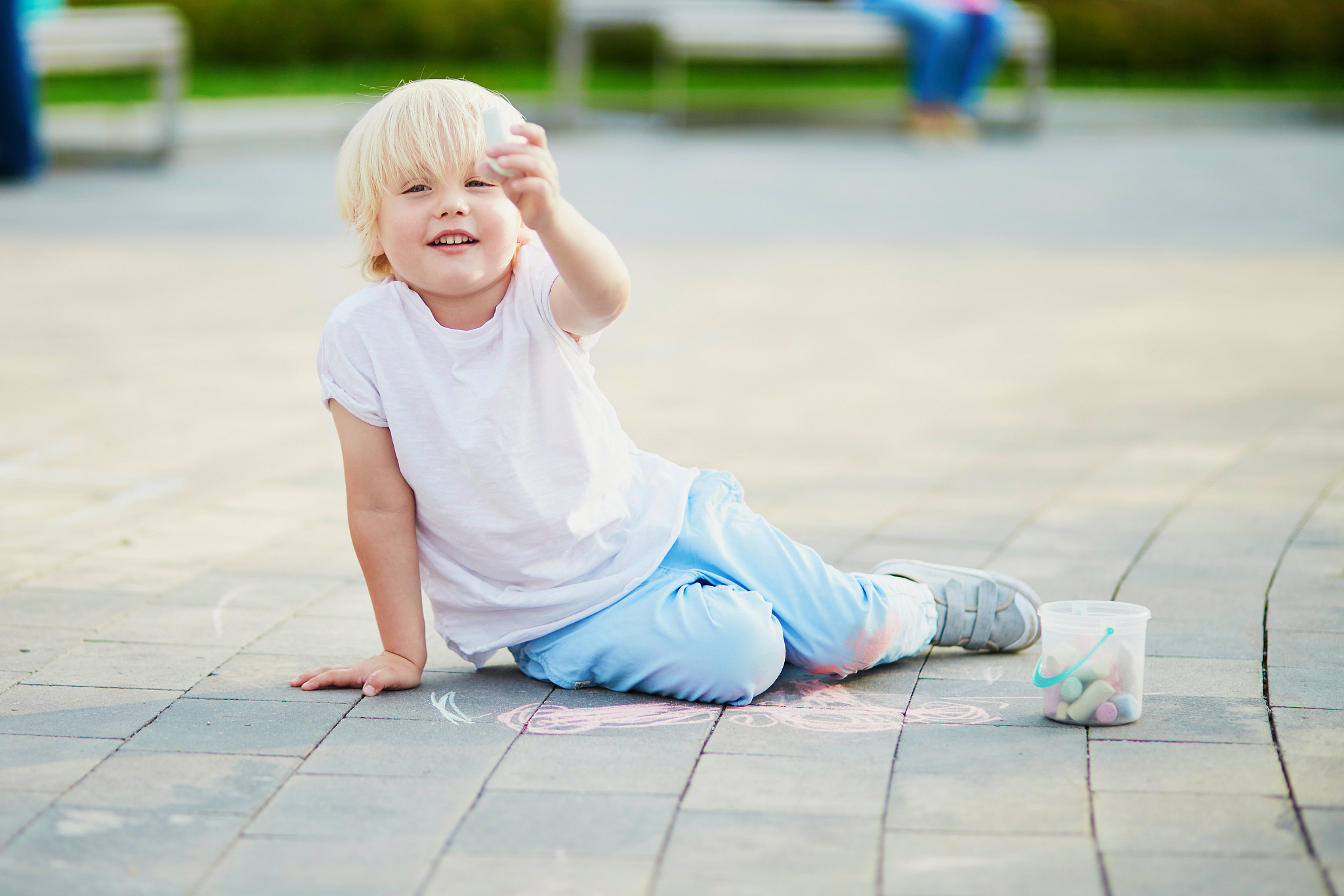 little boy drawing with chalks on asphalt
