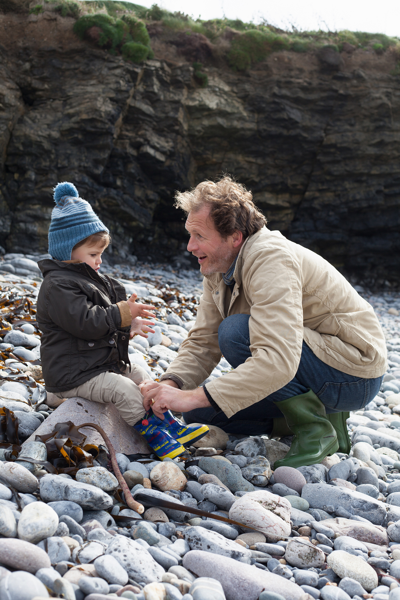 father and son playing on rocky beach