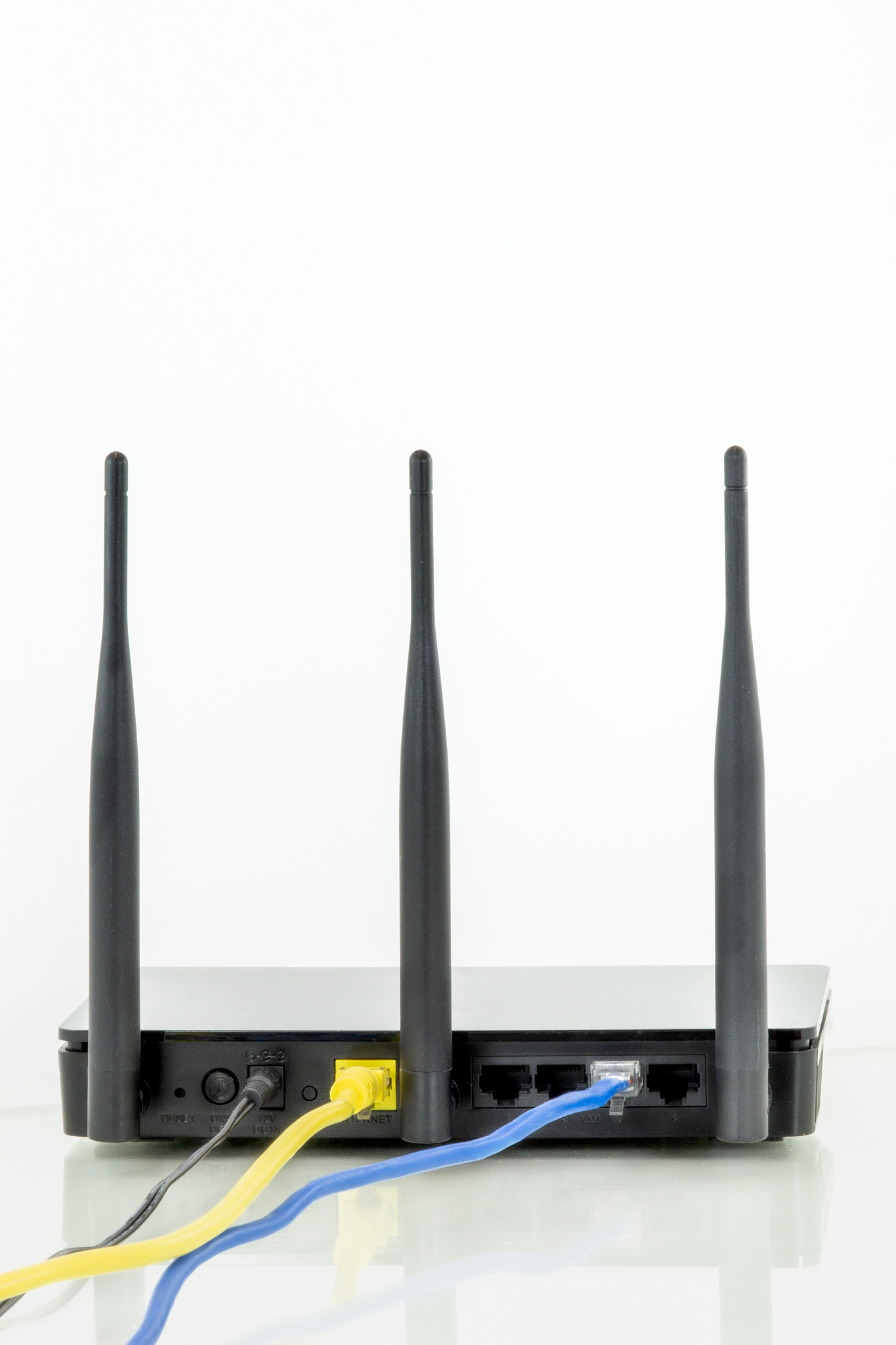 wireless router with three antennas and cables connected. white 