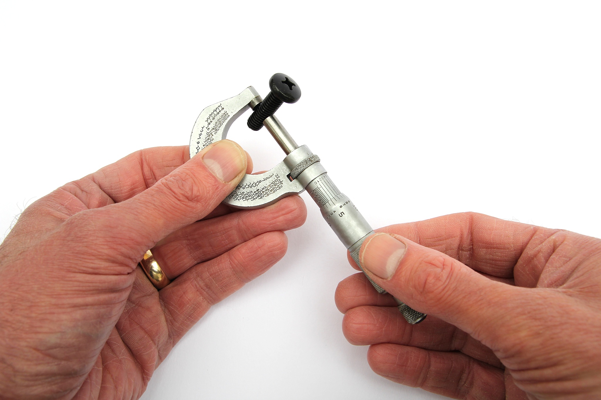 man's hands seen using a vintage imperial micrometer to measure 