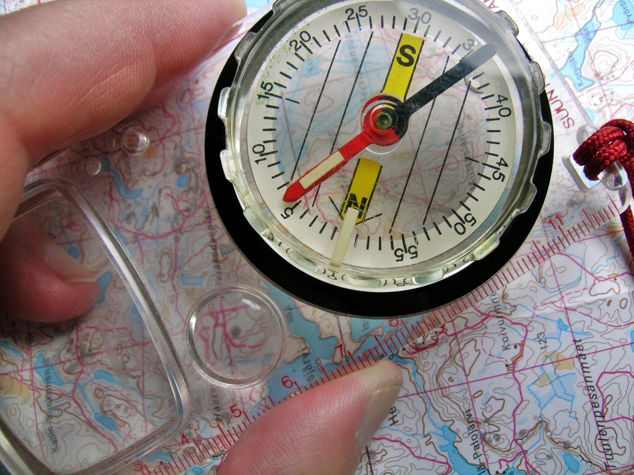 close-up of person holding compass over map