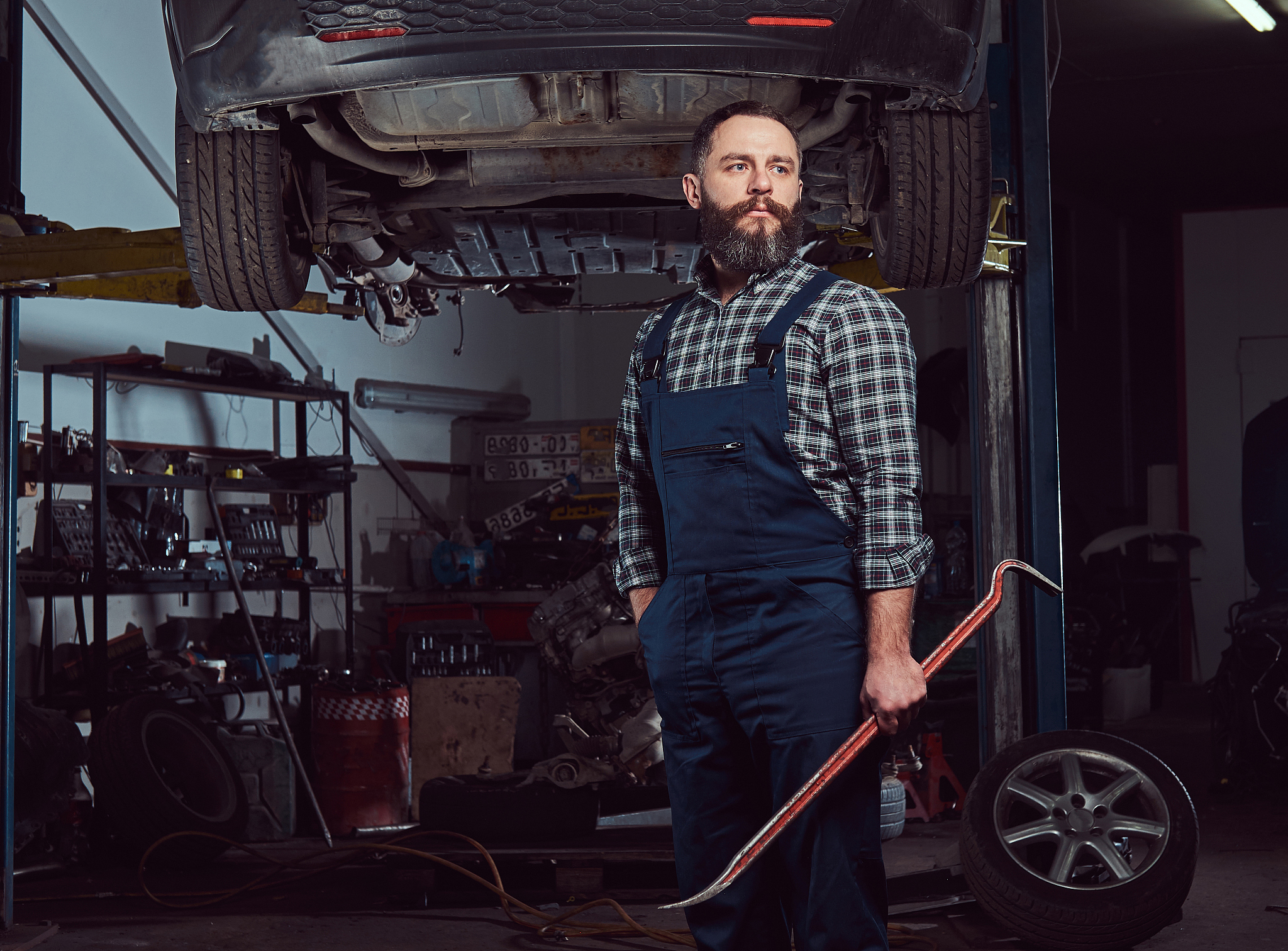two bearded brutal mechanics repair a car on a lift in the garag