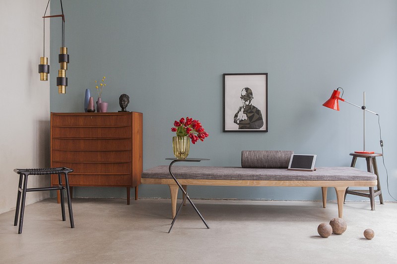 retro chest of drawers next to couch against pale blue wall