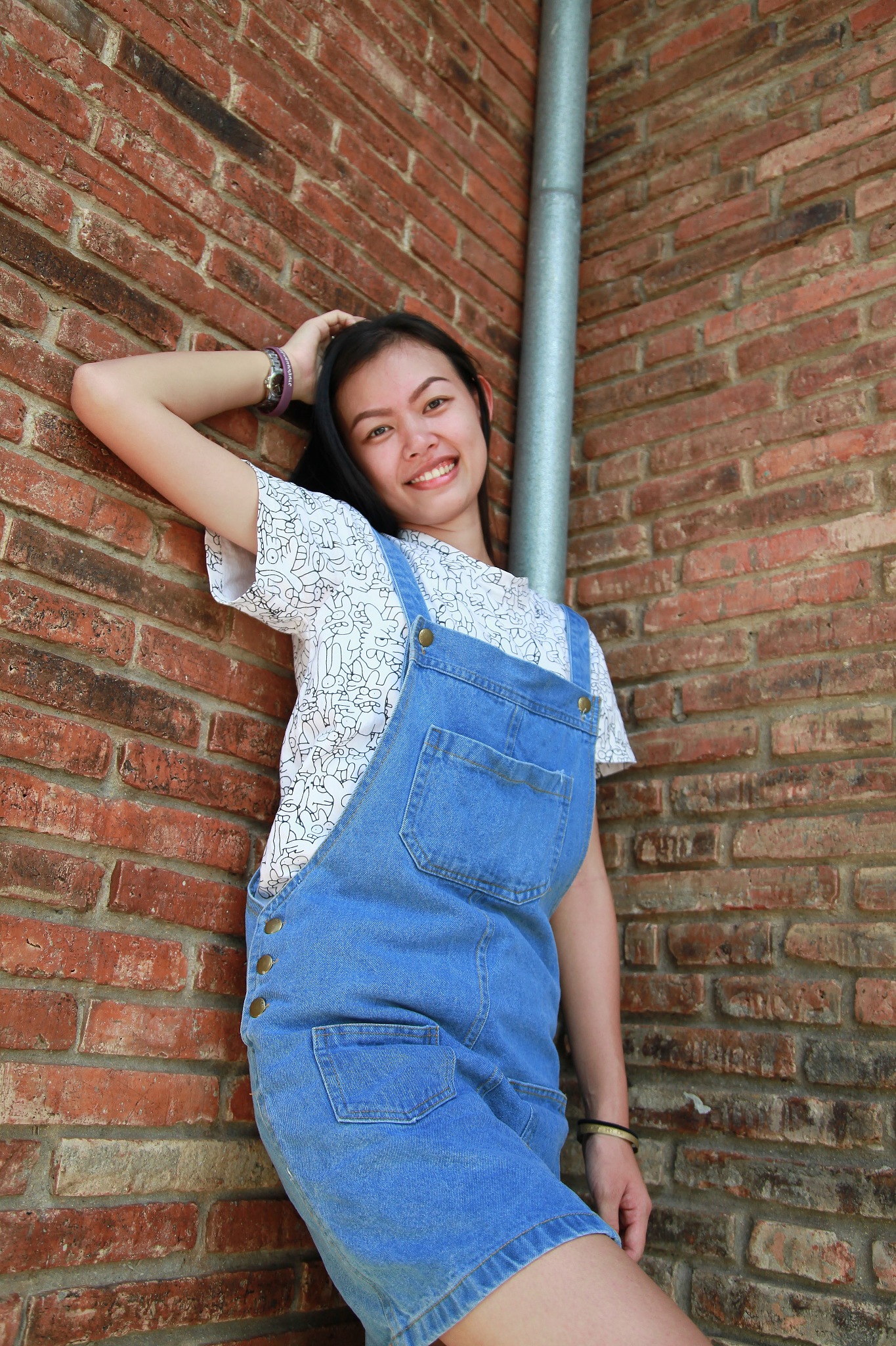 portrait of smiling young woman against brick wall