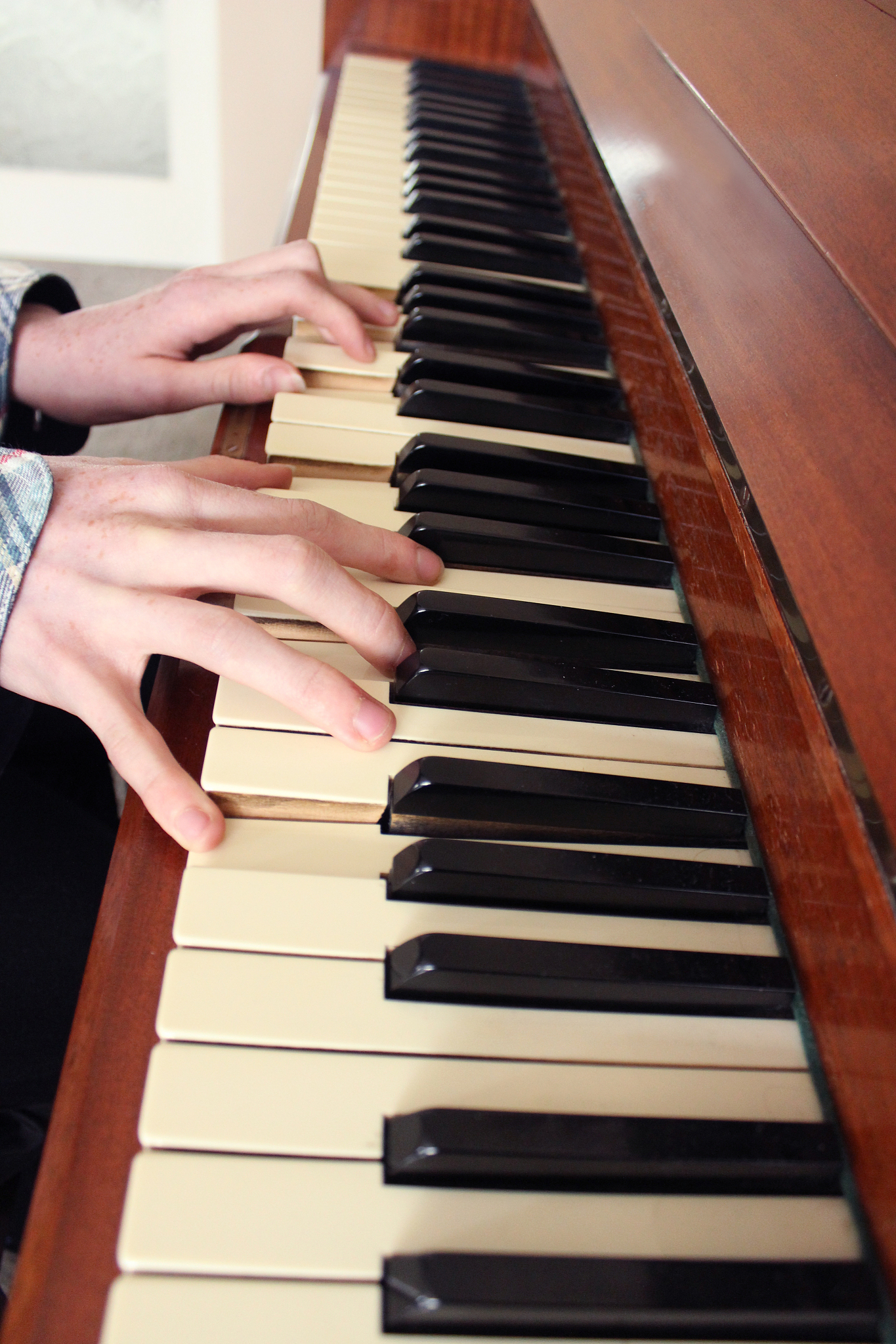 image of teenage boy playing the piano, wooden piano keyboard