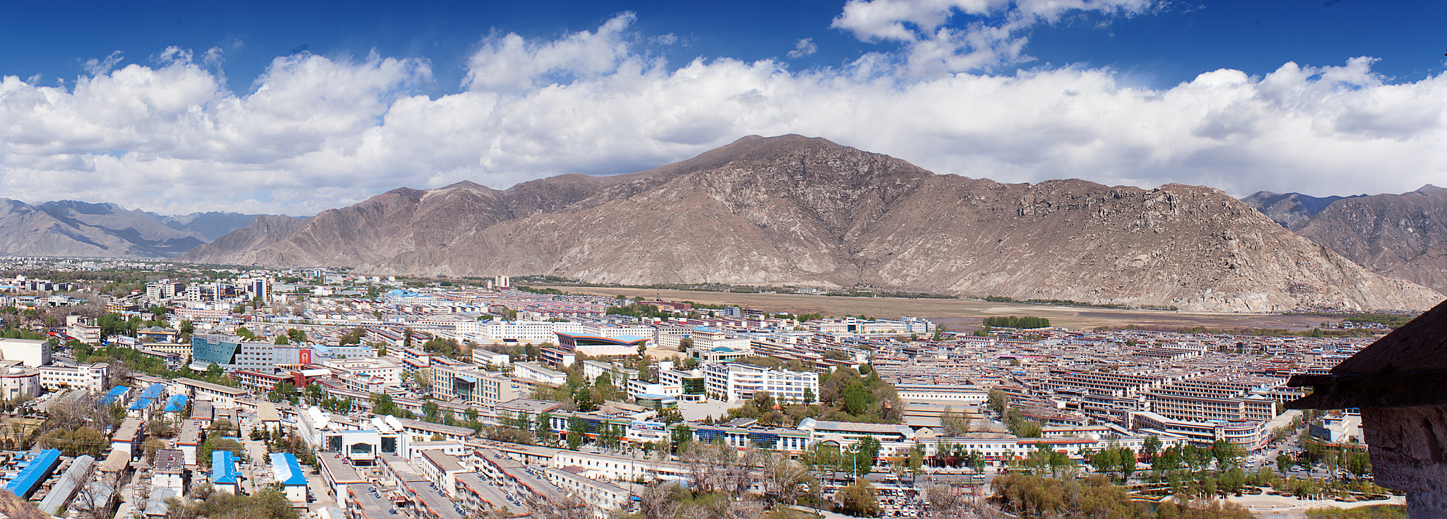 cityscape and mountains against cloudy sky on sunny day