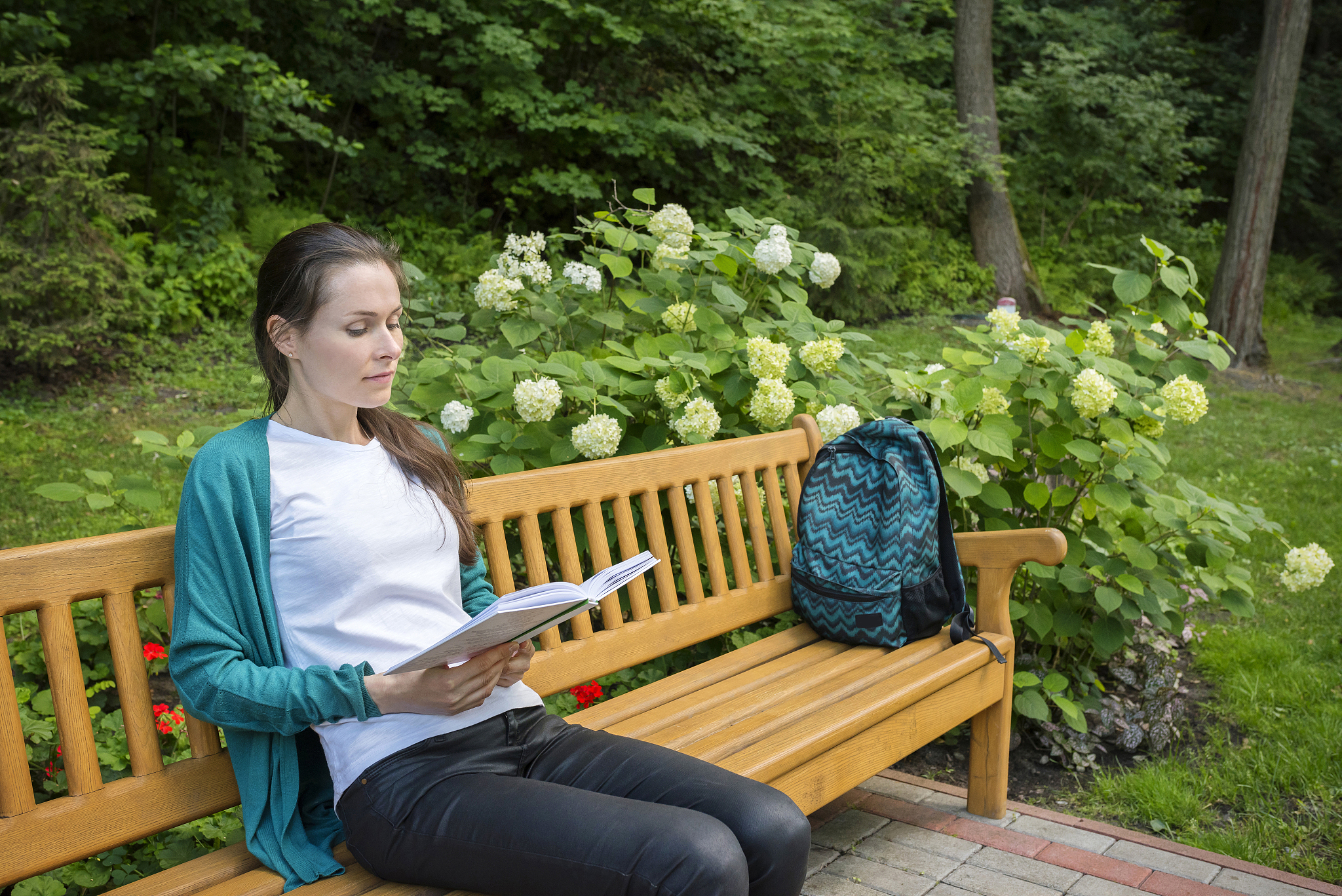 young beautiful woman sitting on a bench and reading a book in t