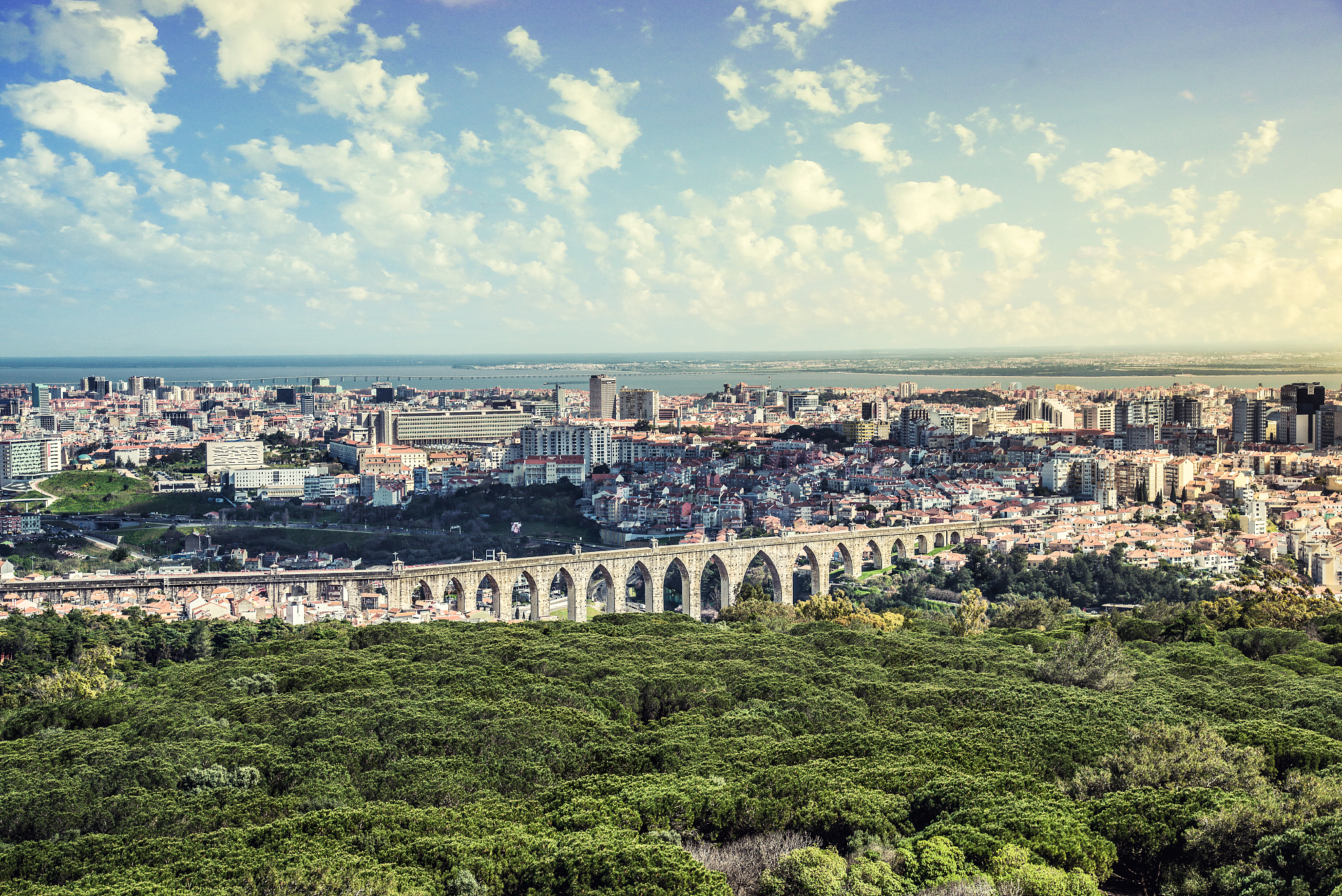 aerial view of city by sea against cloudy sky