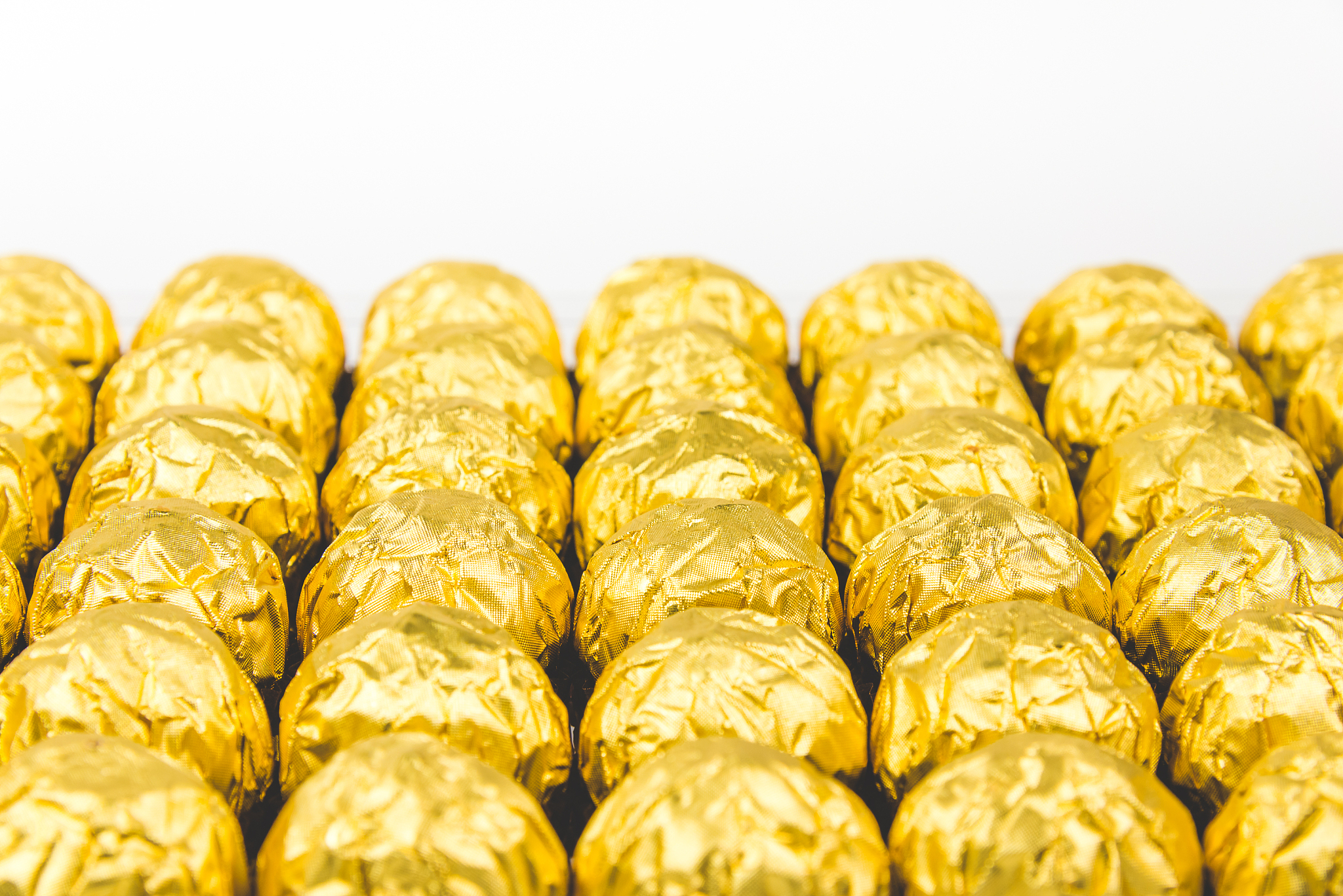 a lot of shiny golden chocolate wrapper in line on white backgro