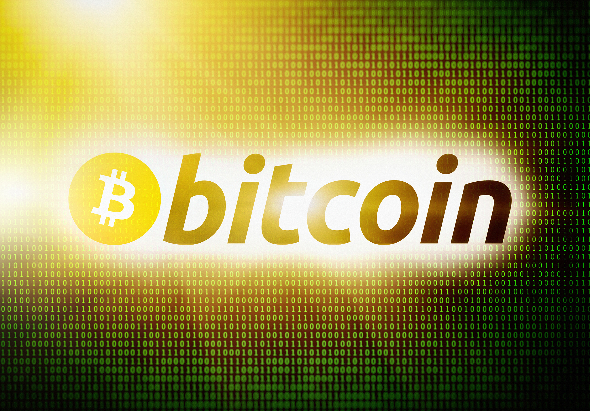bitcoin logo, brightly lit, on screen of binary code