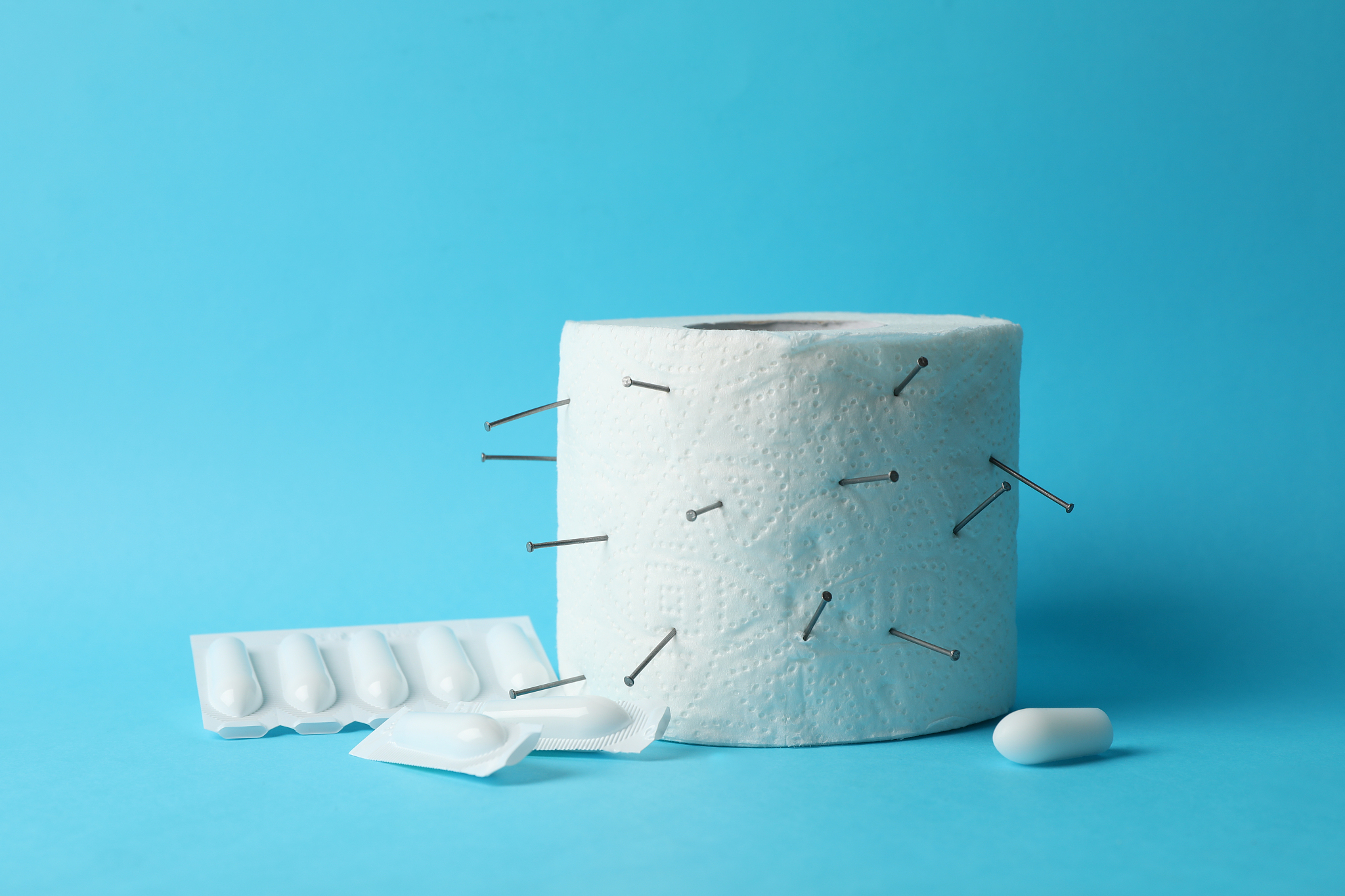toilet paper with nails and candles on blue background. hemorrho