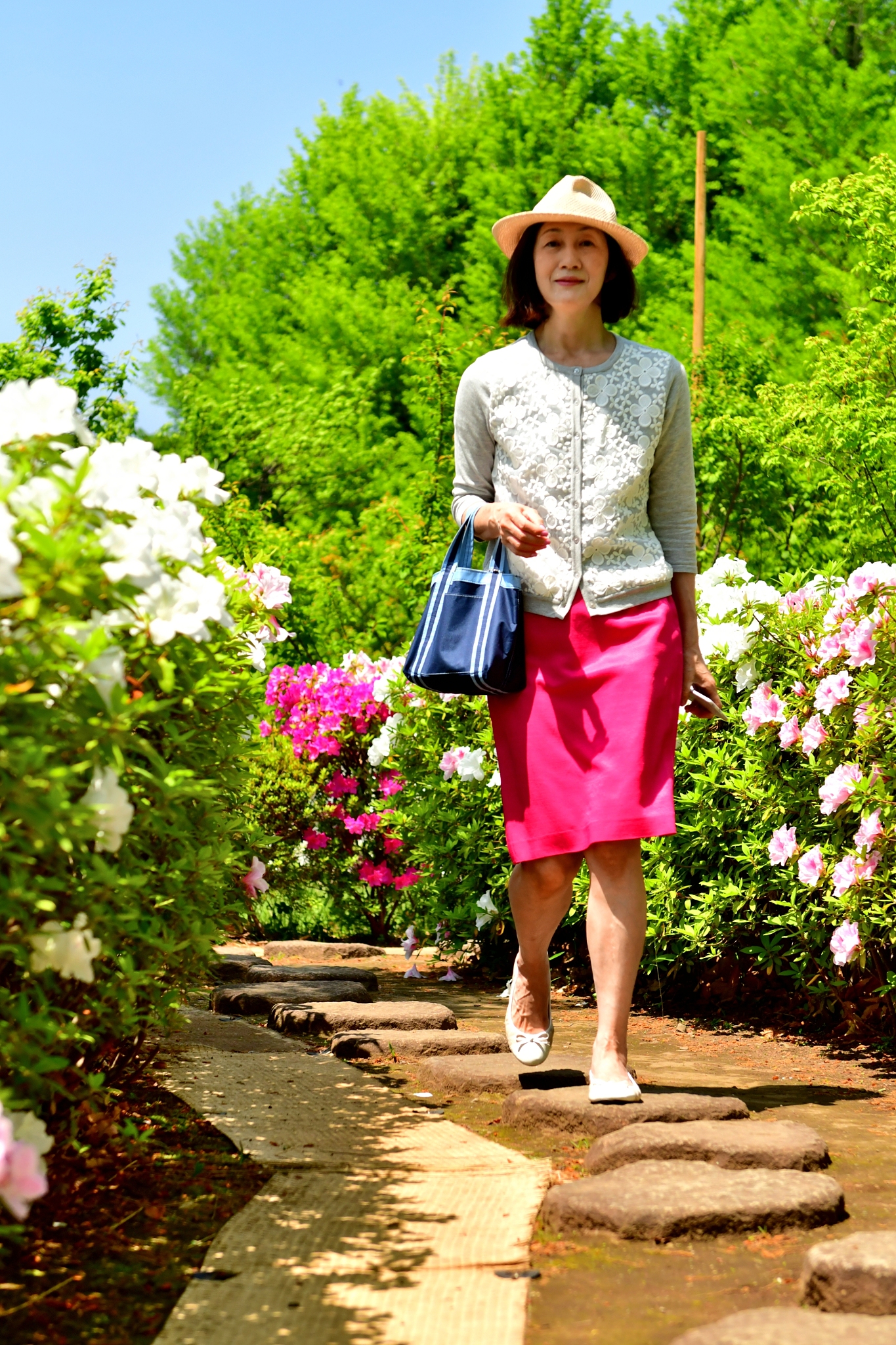 japanese woman walking in park with azalea flowers in full bloom