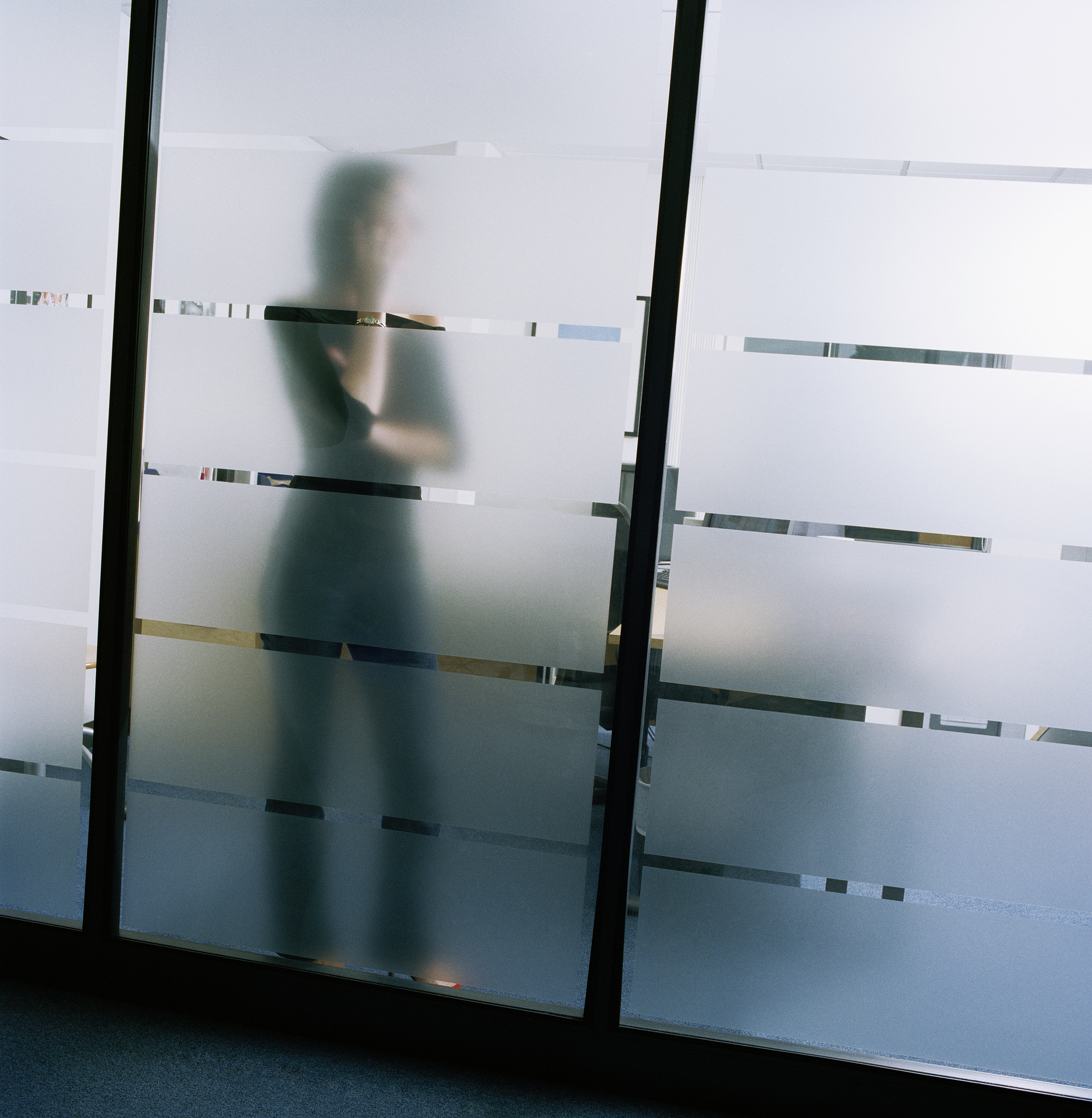 woman using cell phone behind clouded glass