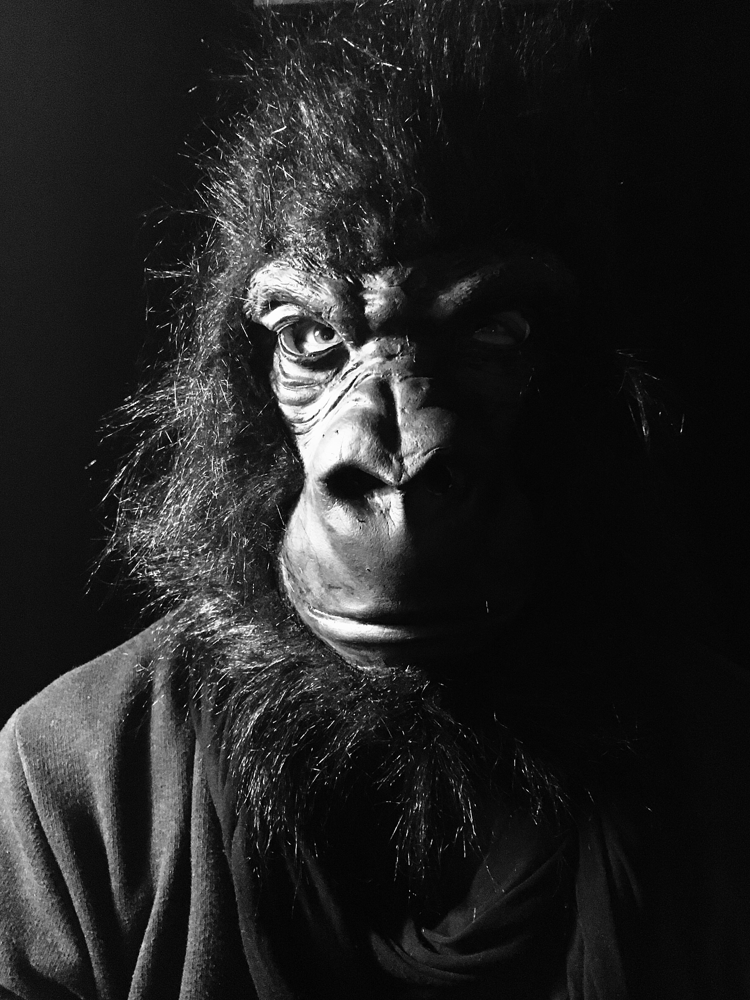 man wearing monkey mask against black background