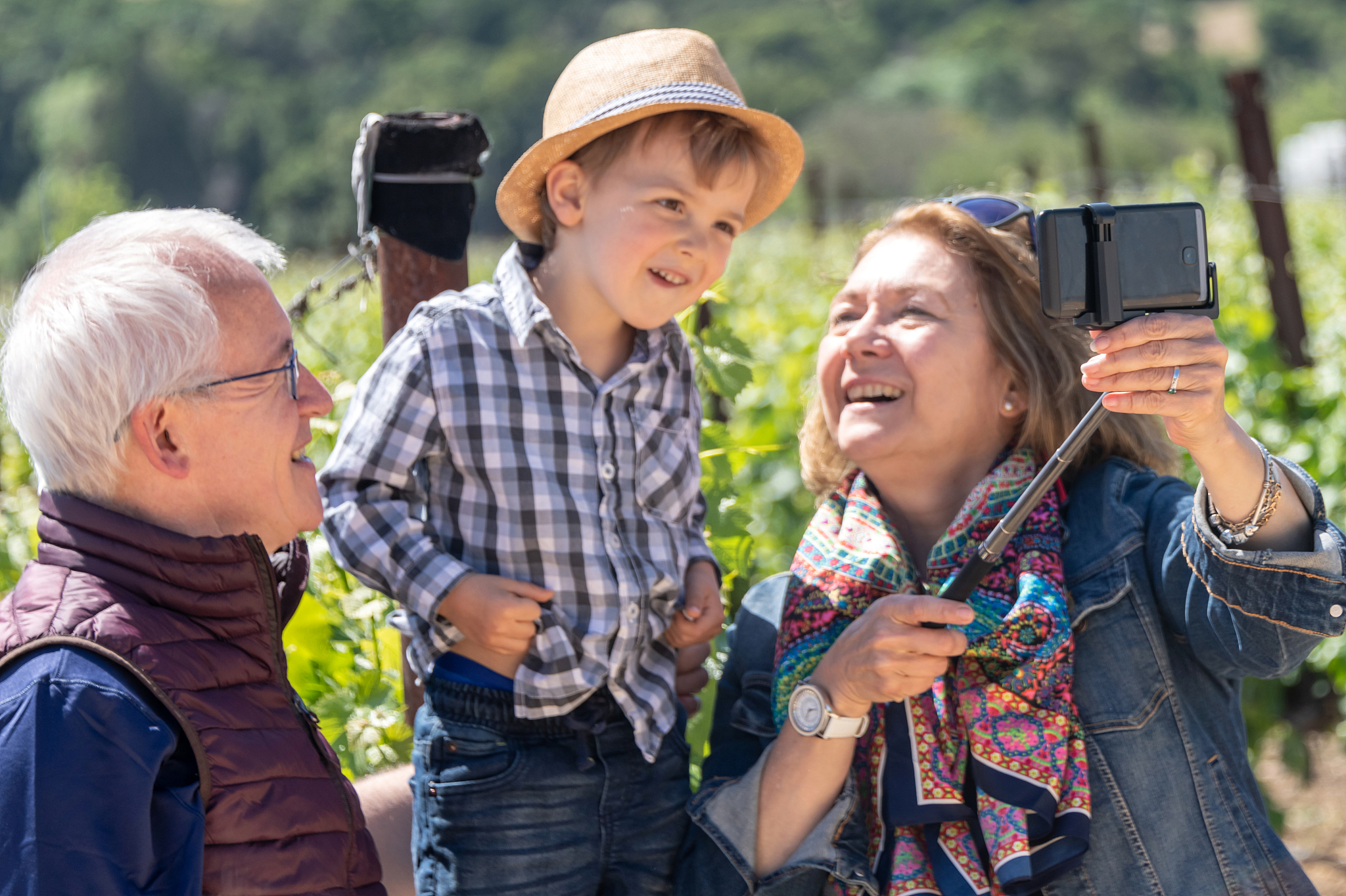 senior couple and their grandson taking a selfie at the vineyard