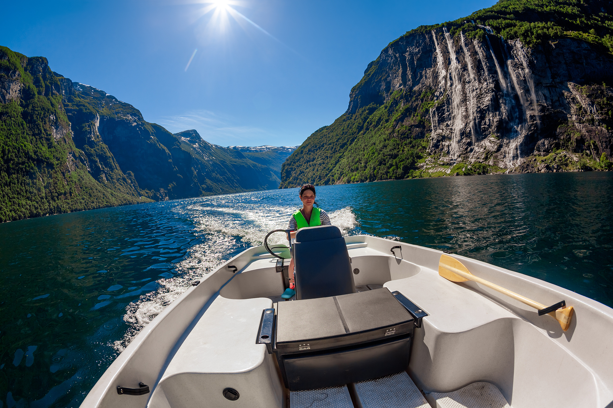 woman driving a motor boat seven sisters waterfall on the backgr