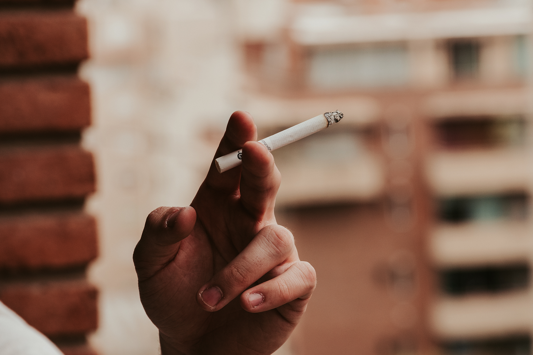 close-up of hand holding lit cigarette outdoors
