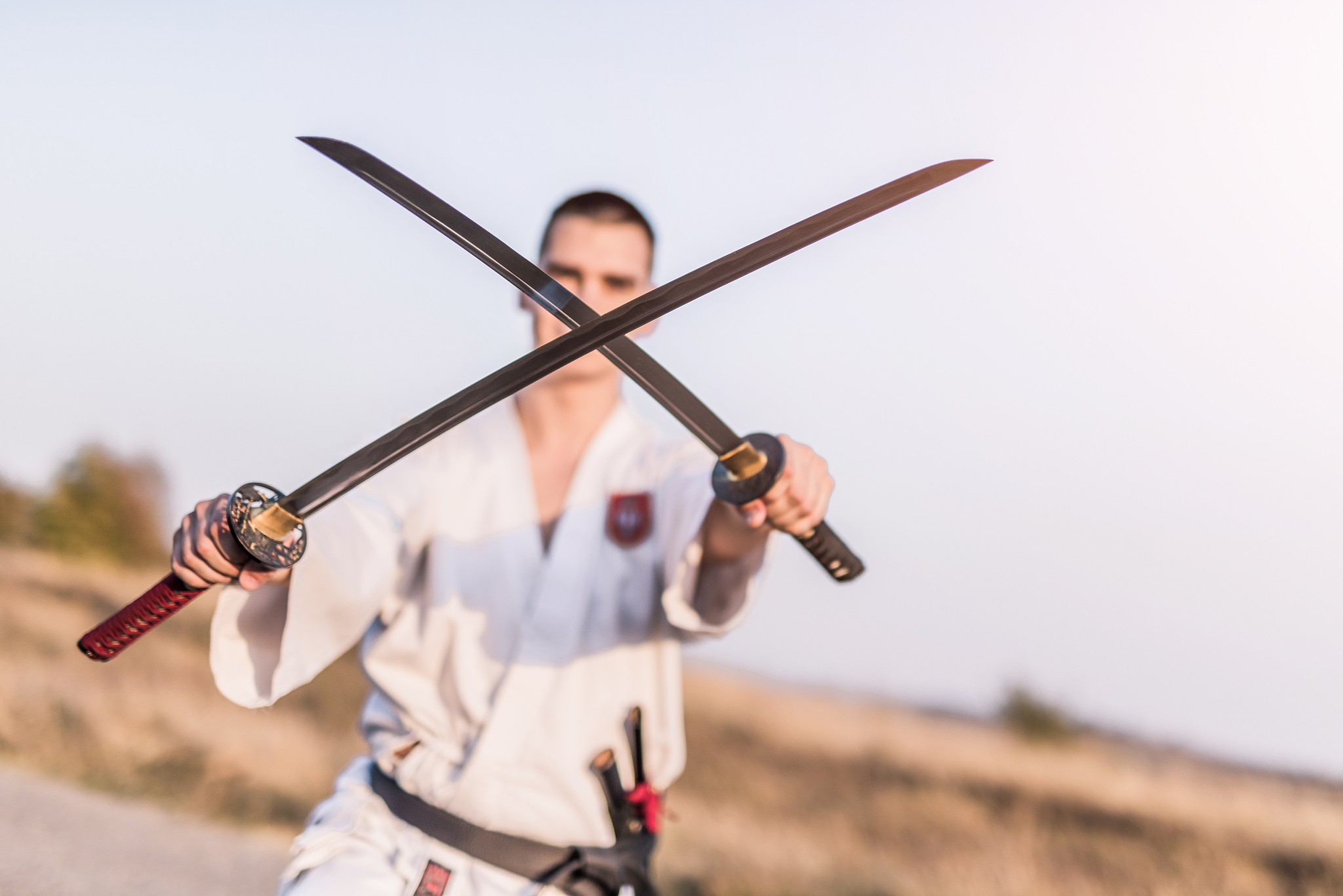 young martial artist holding two katanas together.