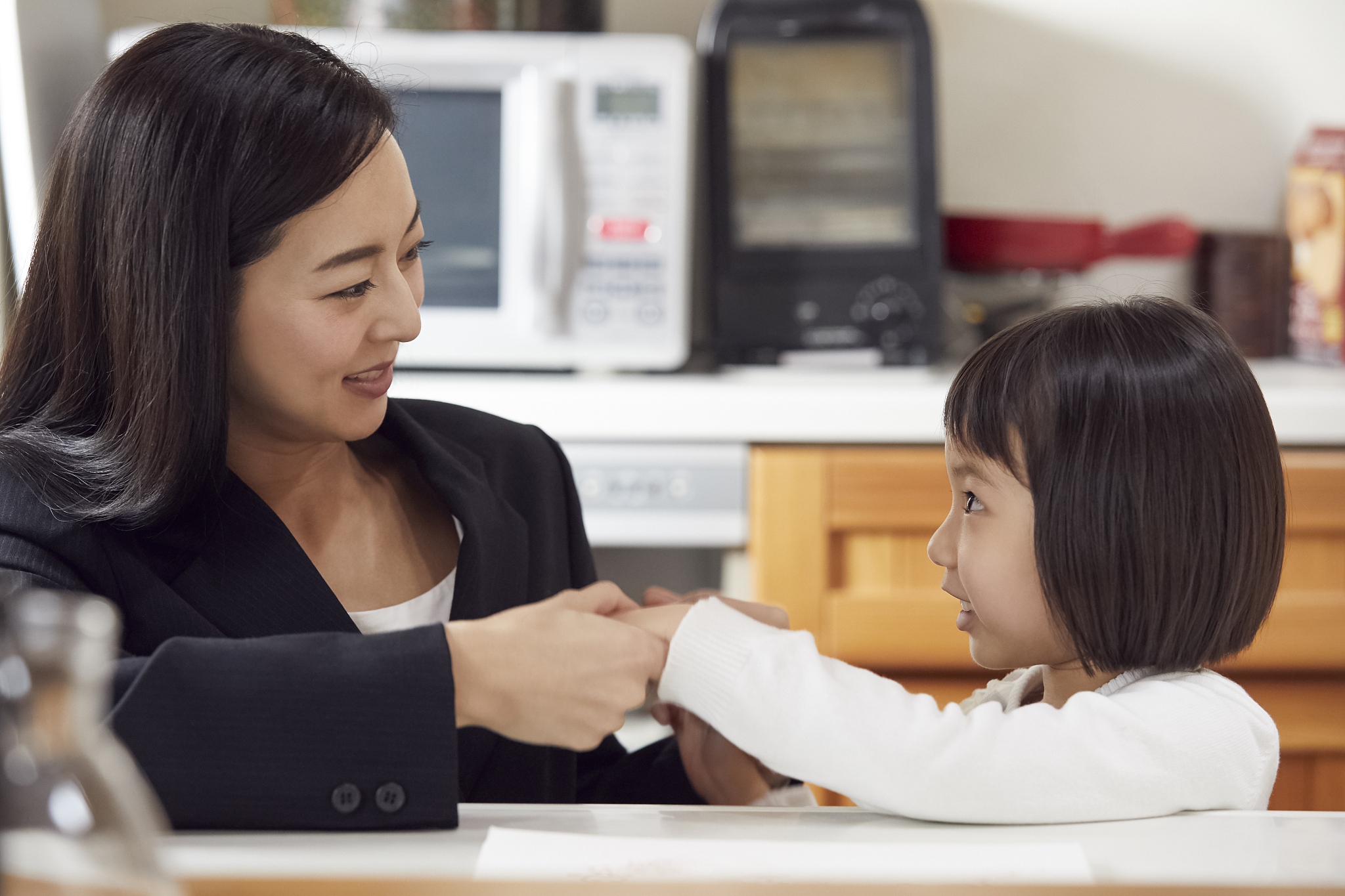 mother taking daughter's hand in kitchen