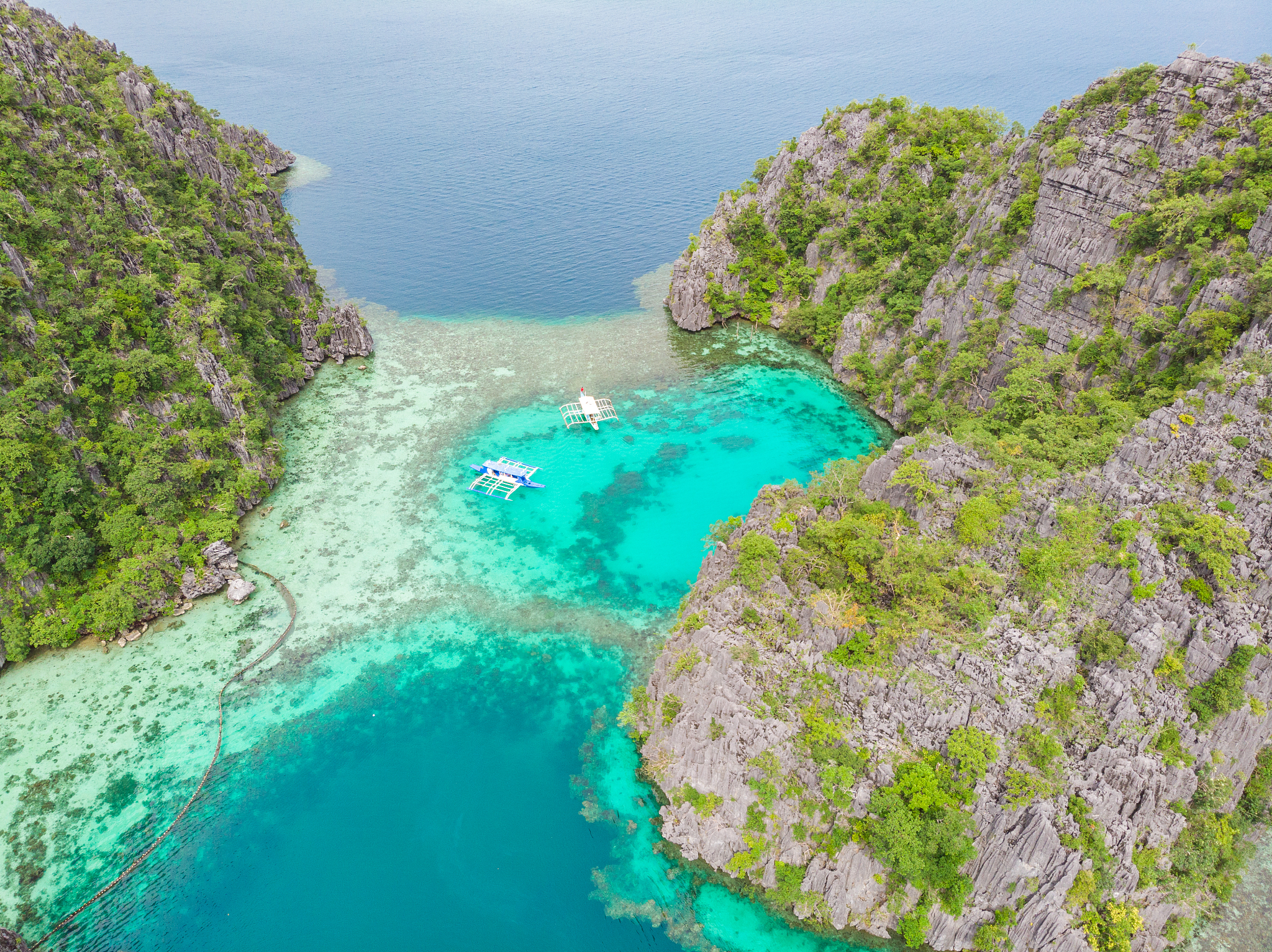 blue crystal water in paradise bay with boats on the wooden pier