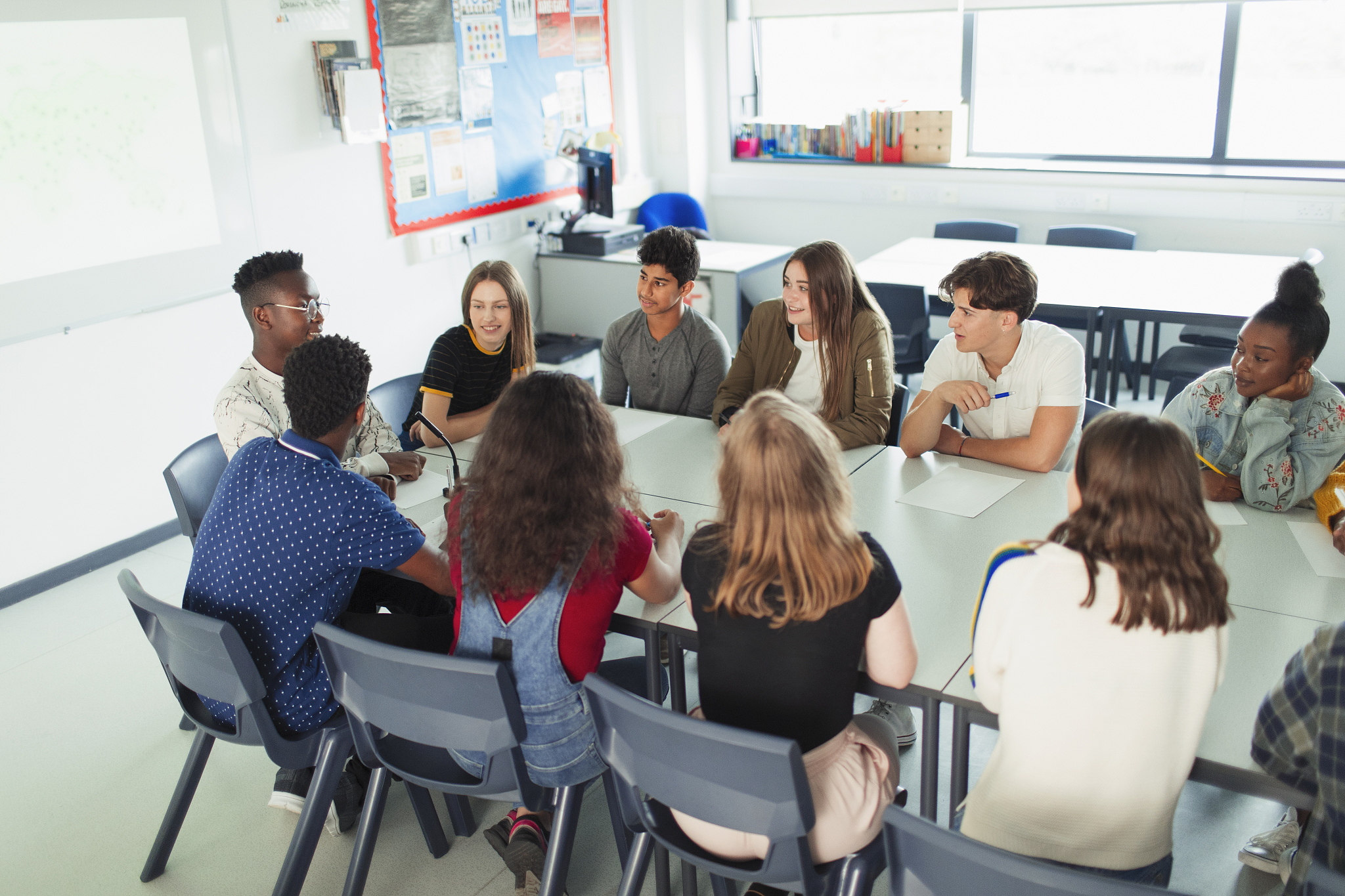 high school students talking in debate class at table in classro