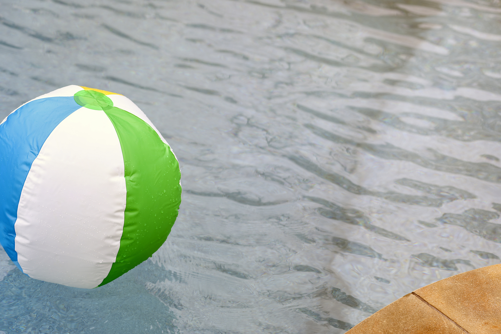 beach ball floating in refreshing swimming pool water.