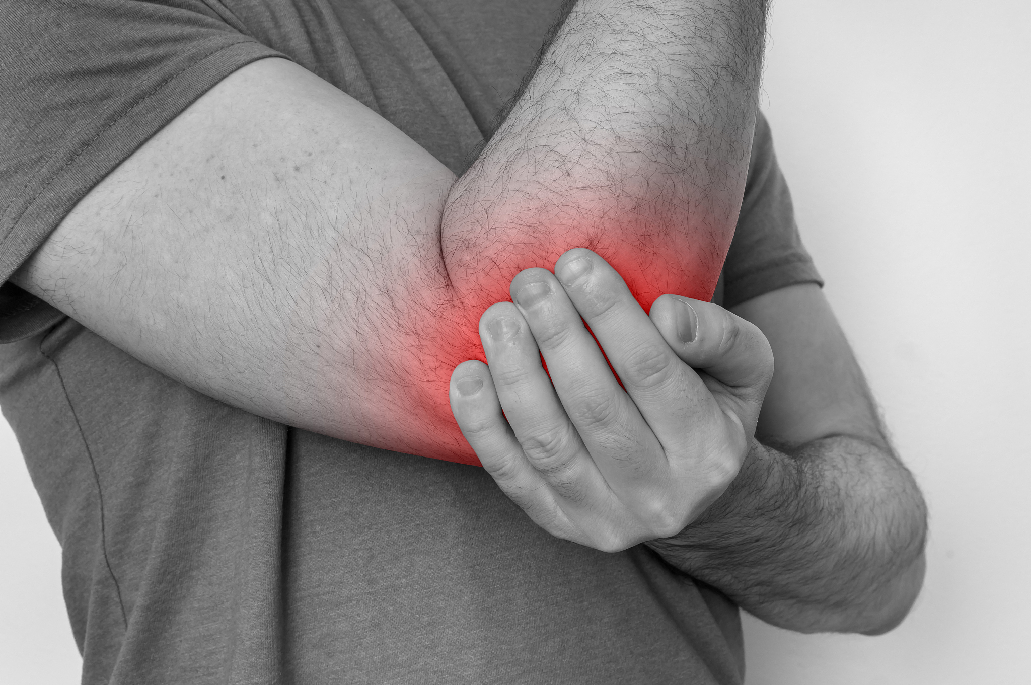 man with elbow pain is holding his aching arm