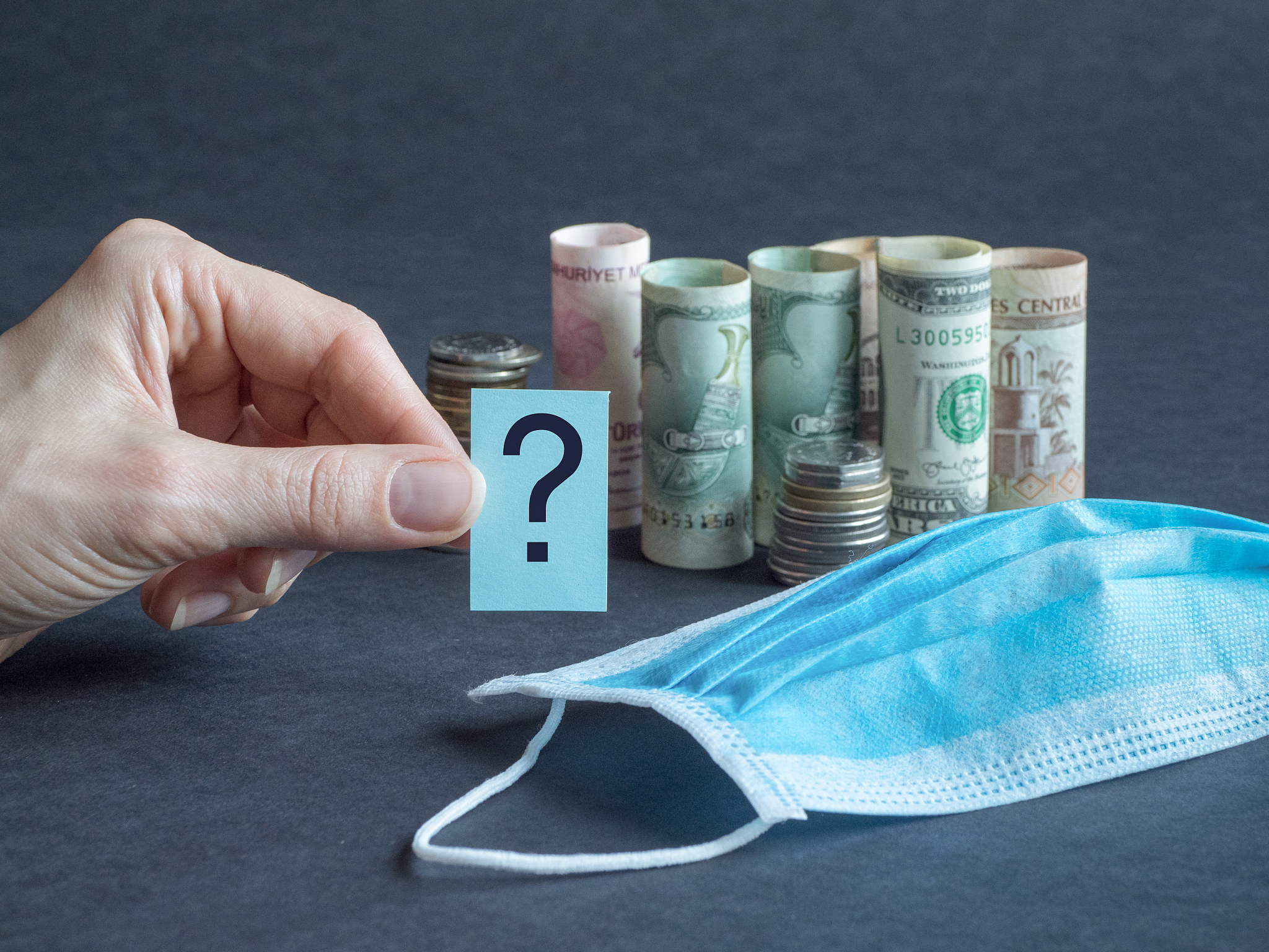 question mark with medical mask and money. pandemic and the econ