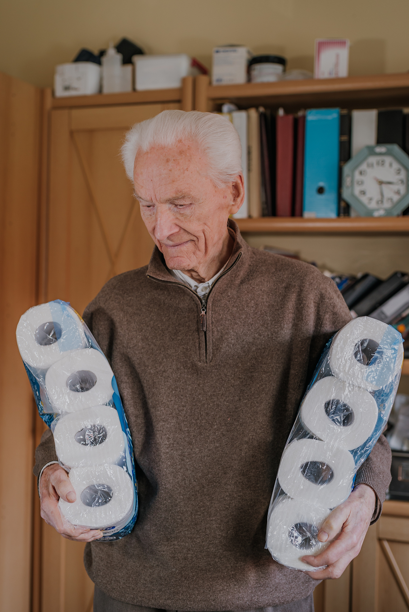 old man holding two packs of toilet paper