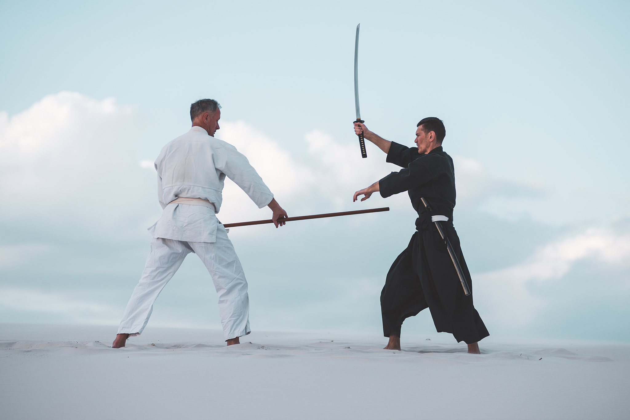 two men practicing japanese martial arts in desert