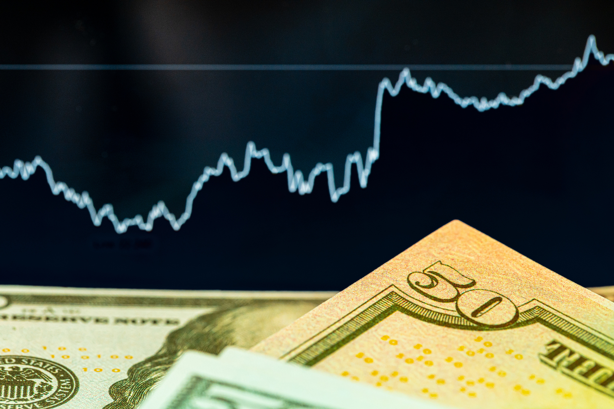 dollars in front of a monitor with a price chart. forex and trad