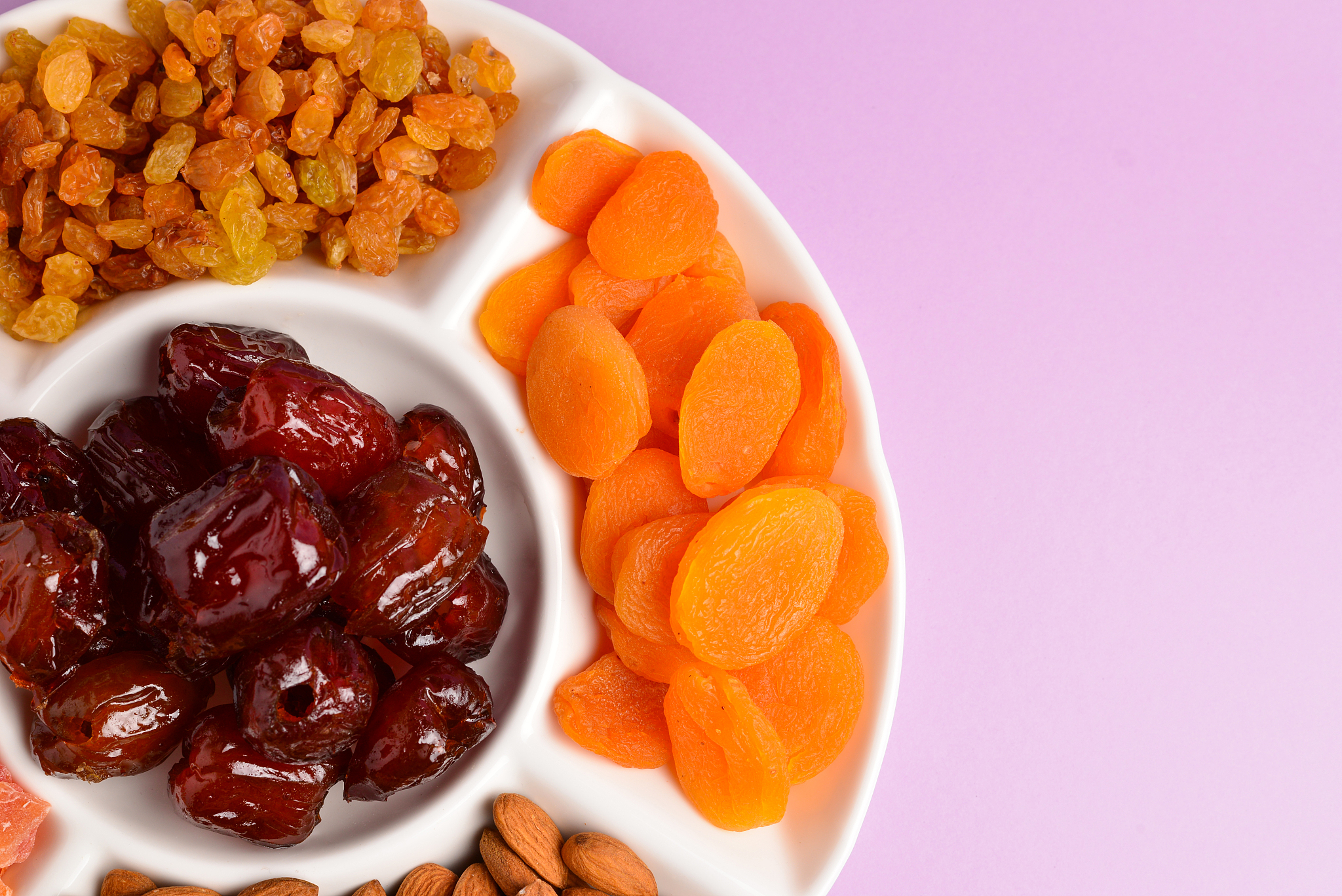 mix of dried fruits and nuts on a white plate. apricot, almond, 