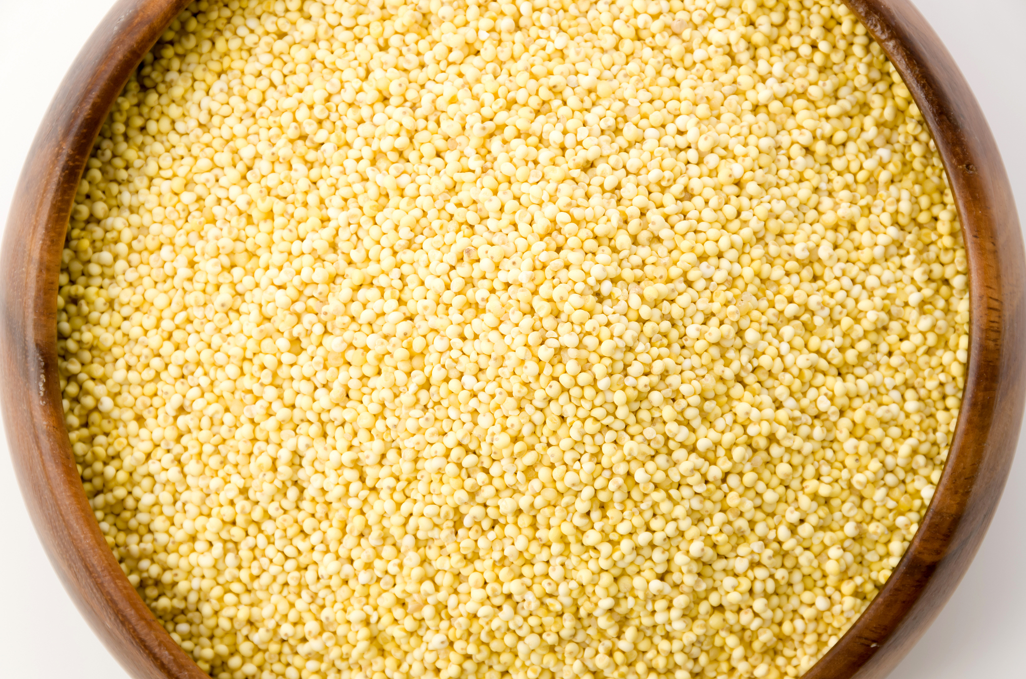 glutinous millet in round wooden bowl on white background
