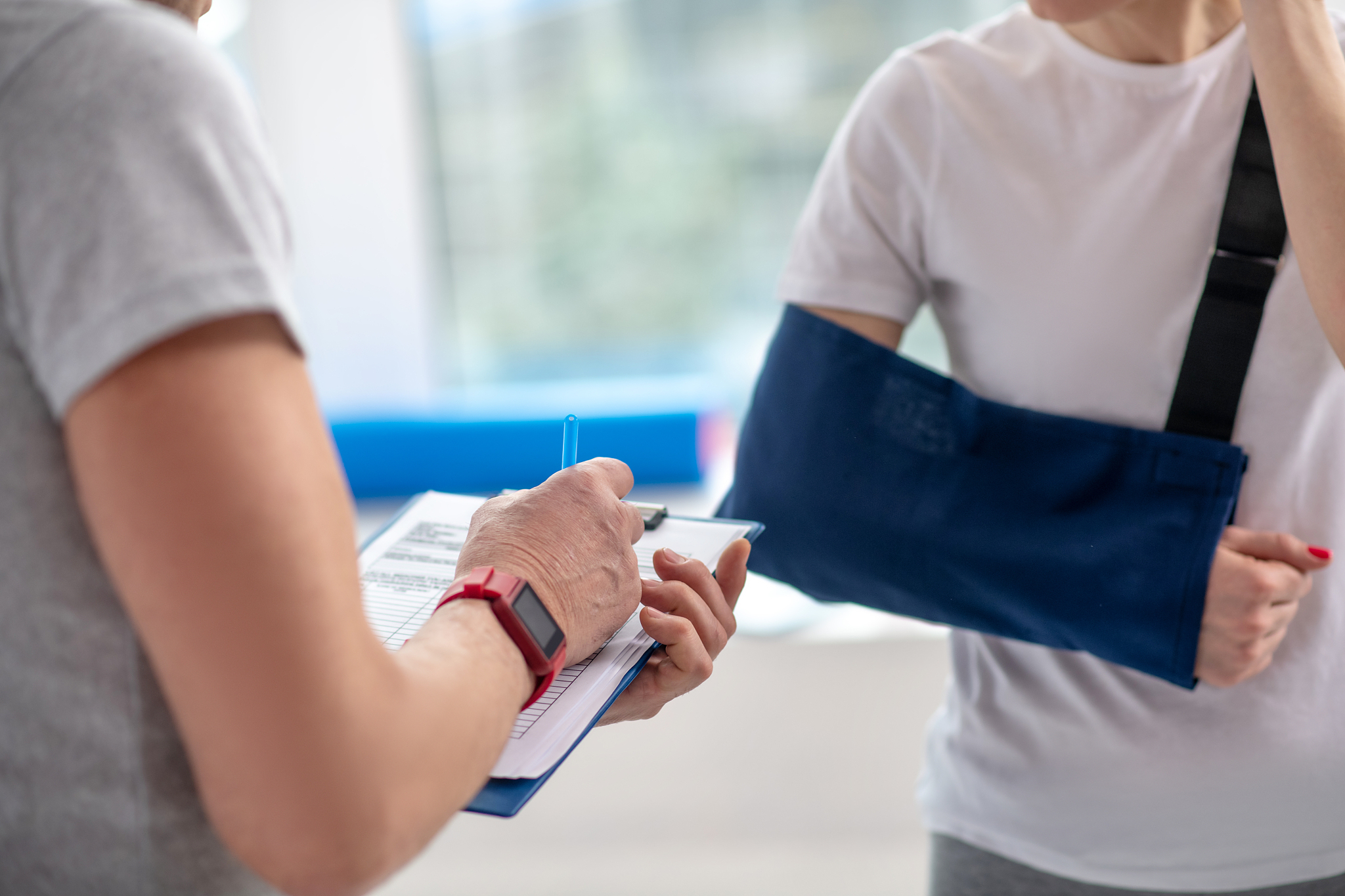 male physiotherapist hand making notes, female patient standing 