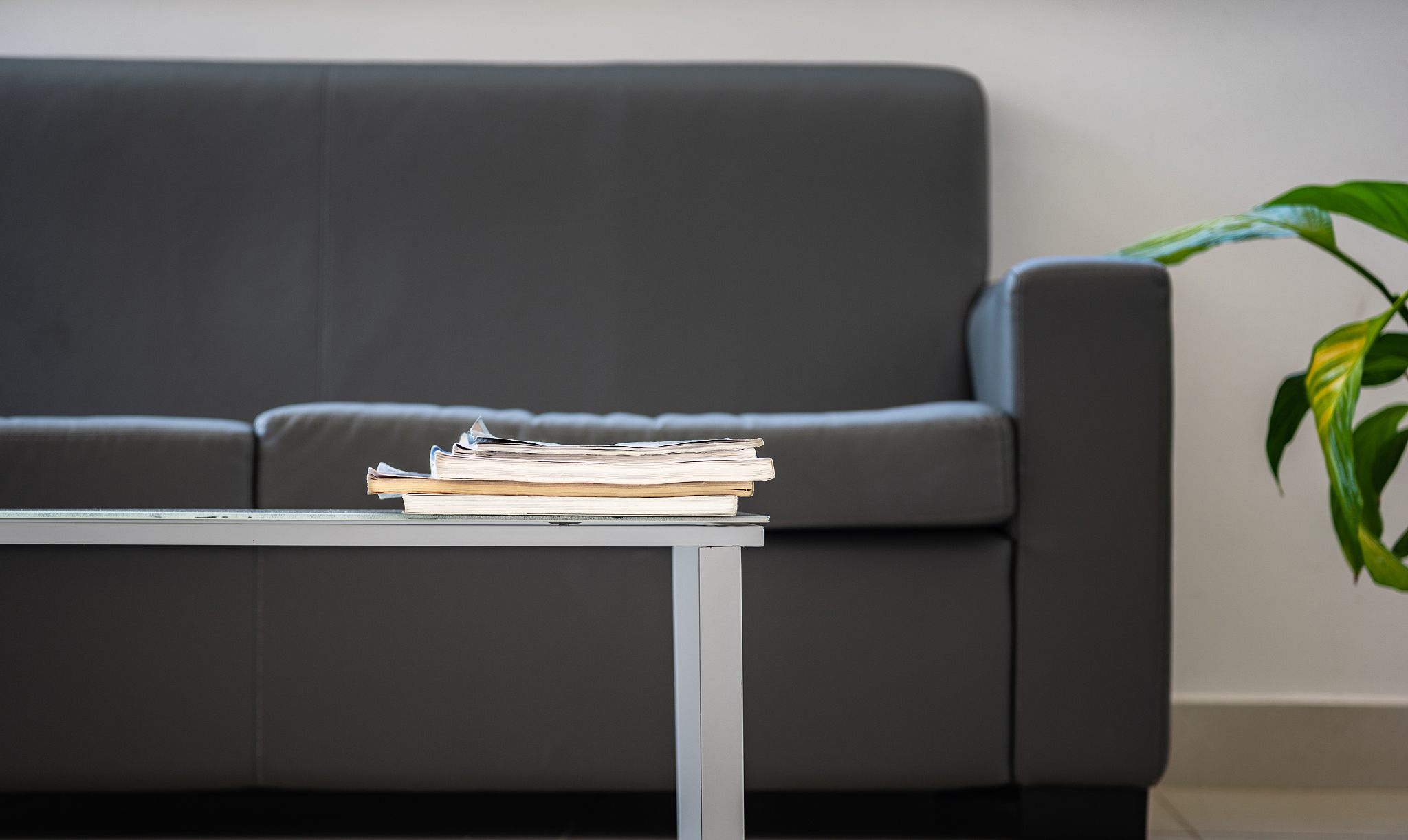 coffee table with stack of magazines against modern grey couch a