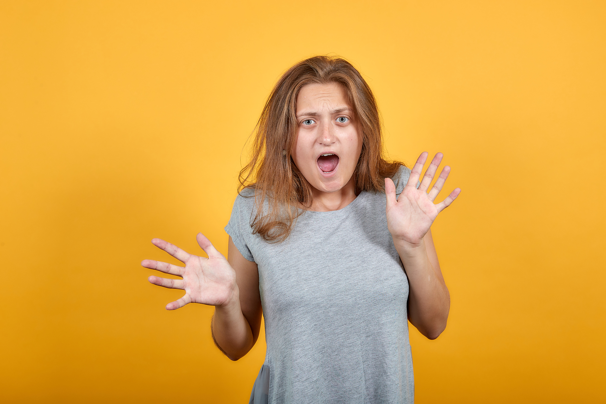 brunette girl in gray t-shirt over isolated orange background sh