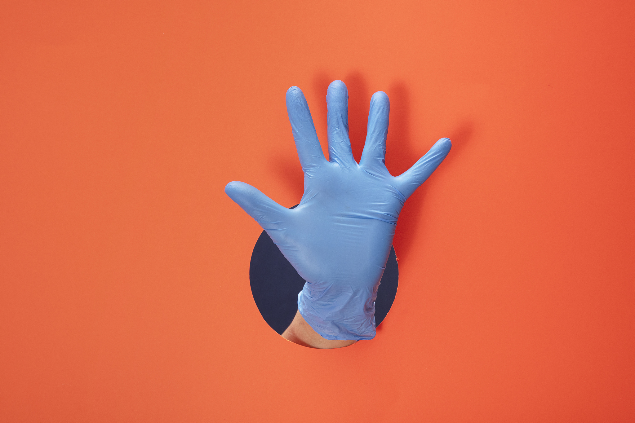 doctor hand with blue medical glove showing number five on orang