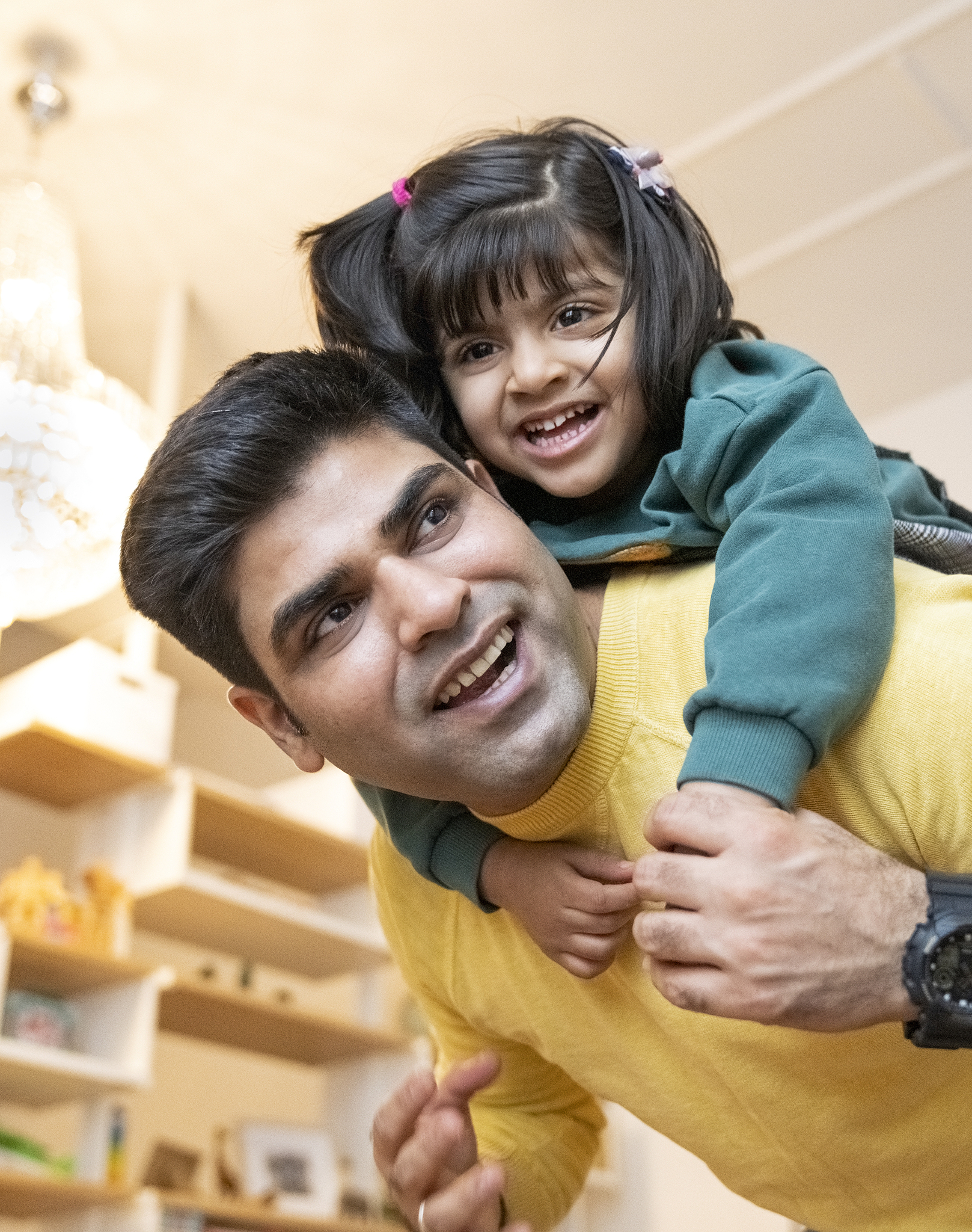 smiling man giving piggyback to daughter at home