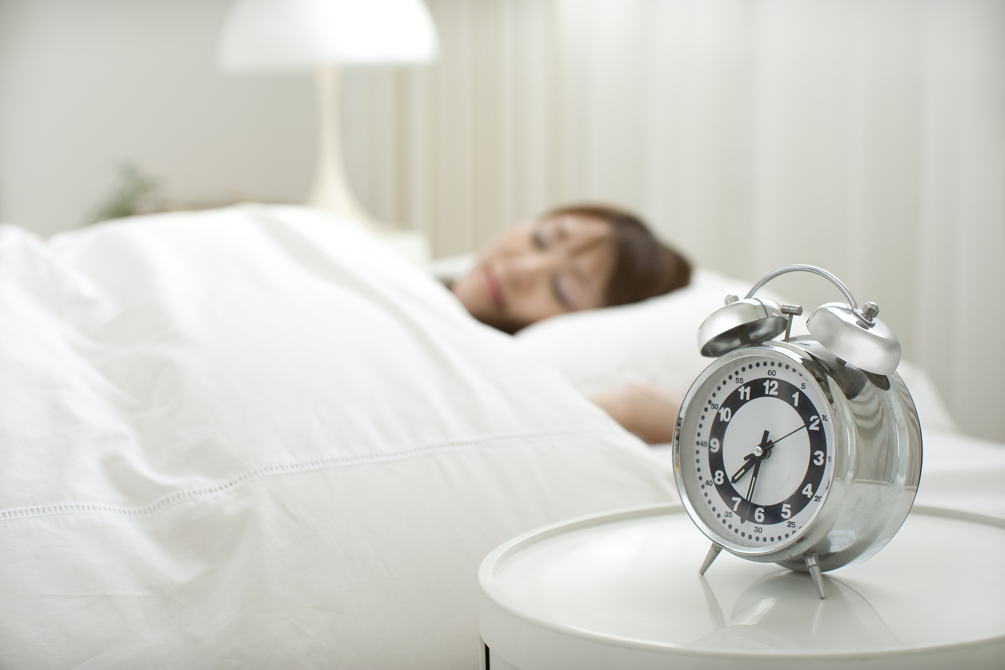 alarm clock,a young woman is sleeping in bed