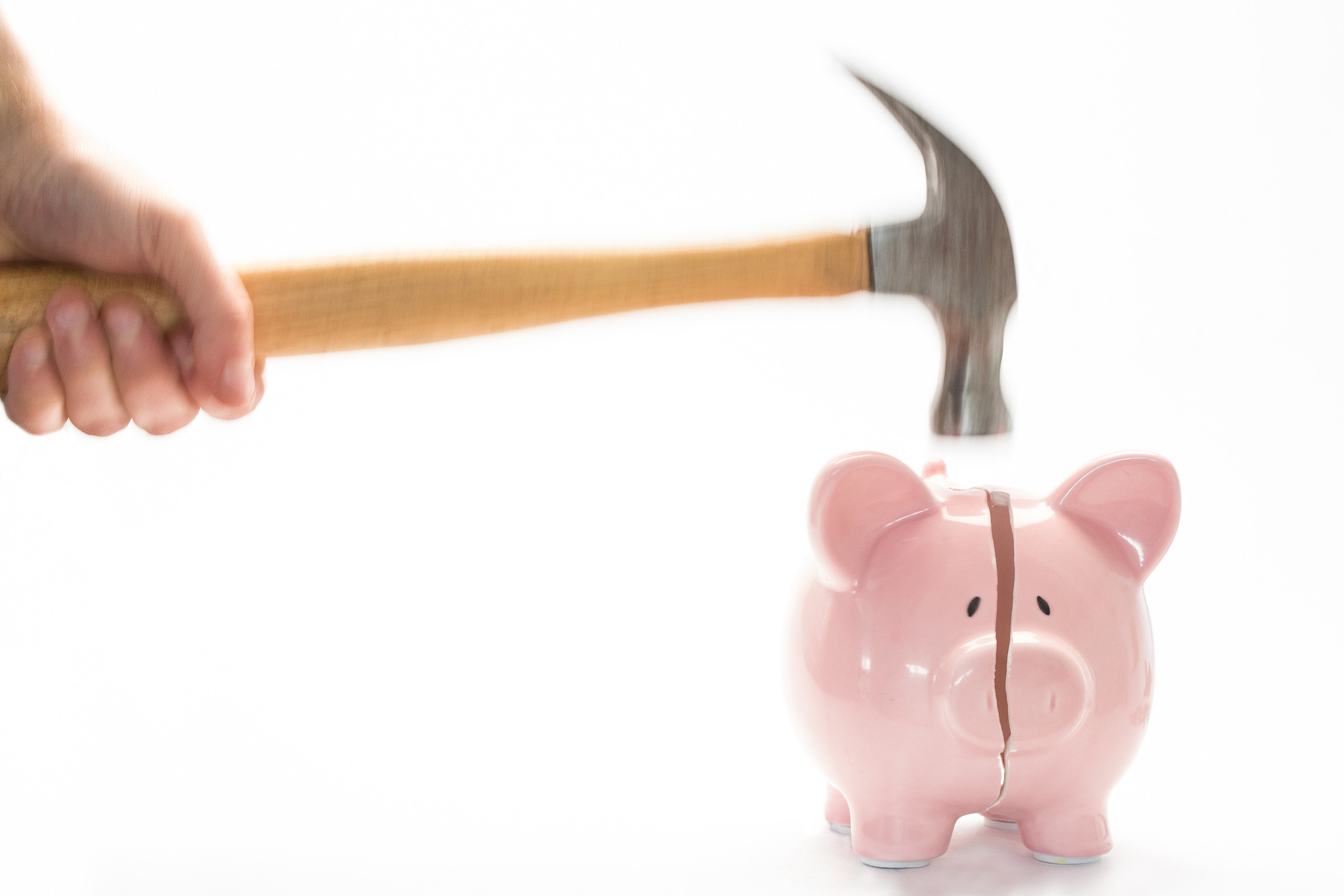 hammer breaking piggy bank on white background