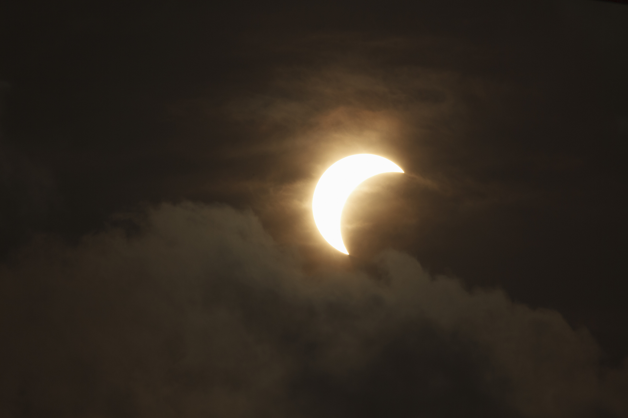 partial solar eclipse through clouds