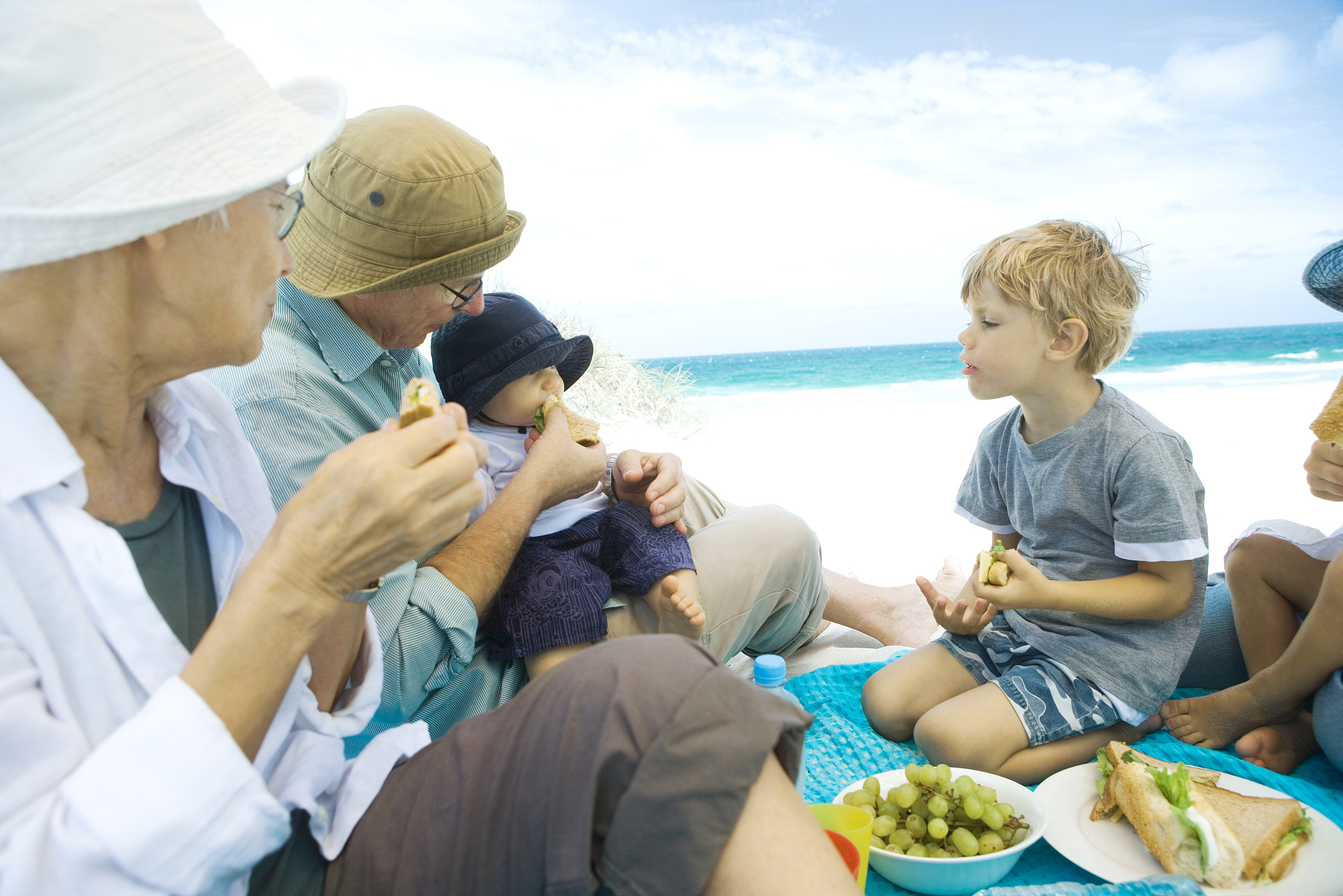 grandparents and grandchildren having picnic on beach