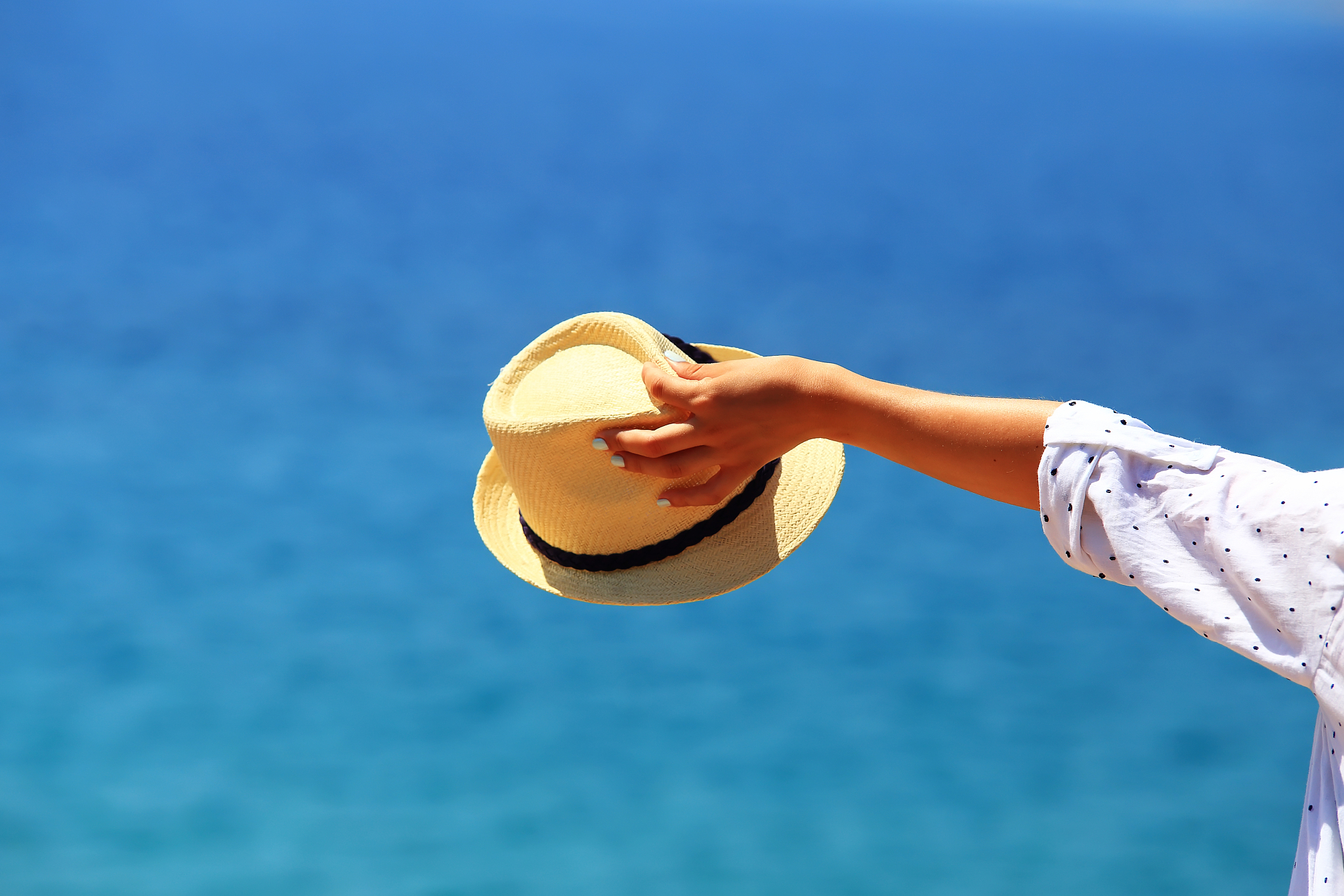 hat in woman hand on blue sea background