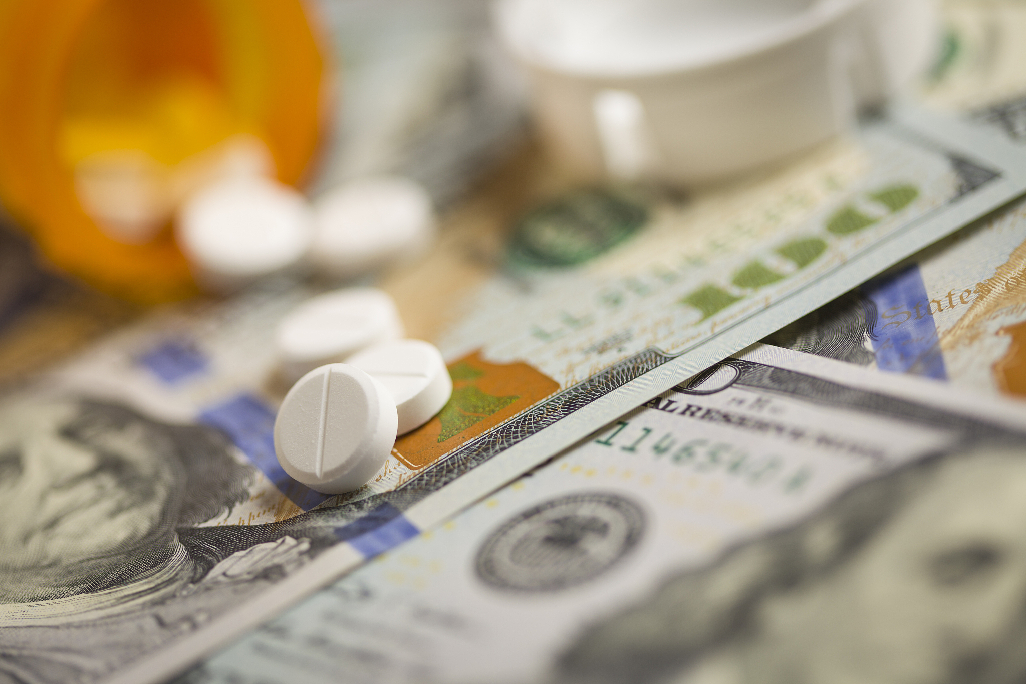 medicine pills scattered on newly designed one hundred dollar bi