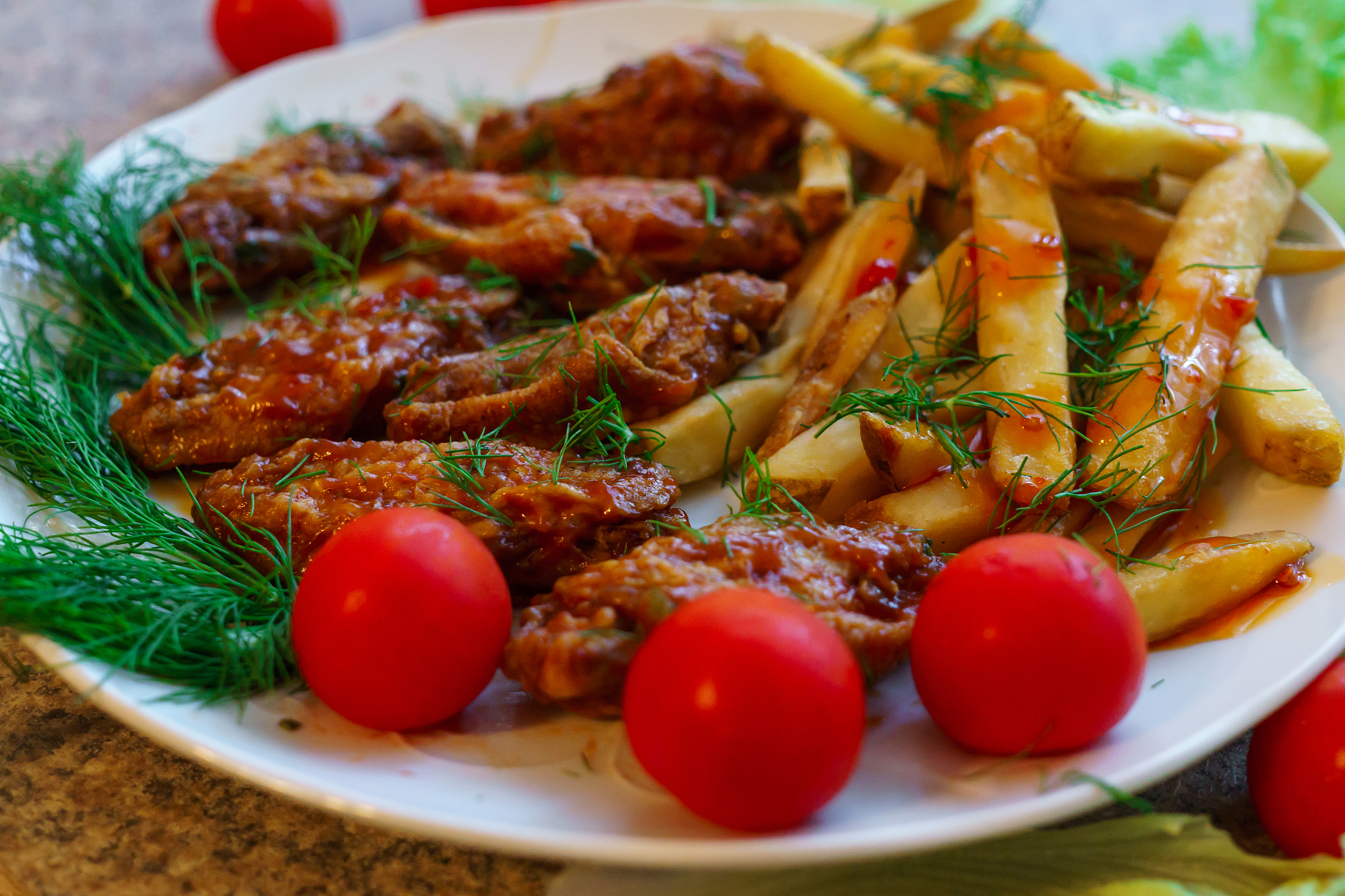 chicken ribs in honey sauce with french fries and vegetables.
