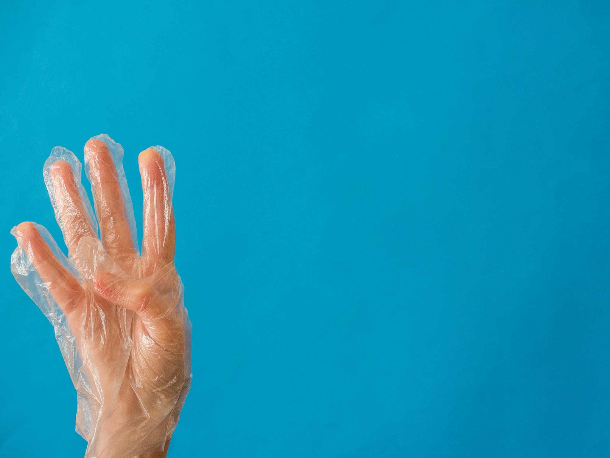 hand with plastic glove with four fingers up on blue background 