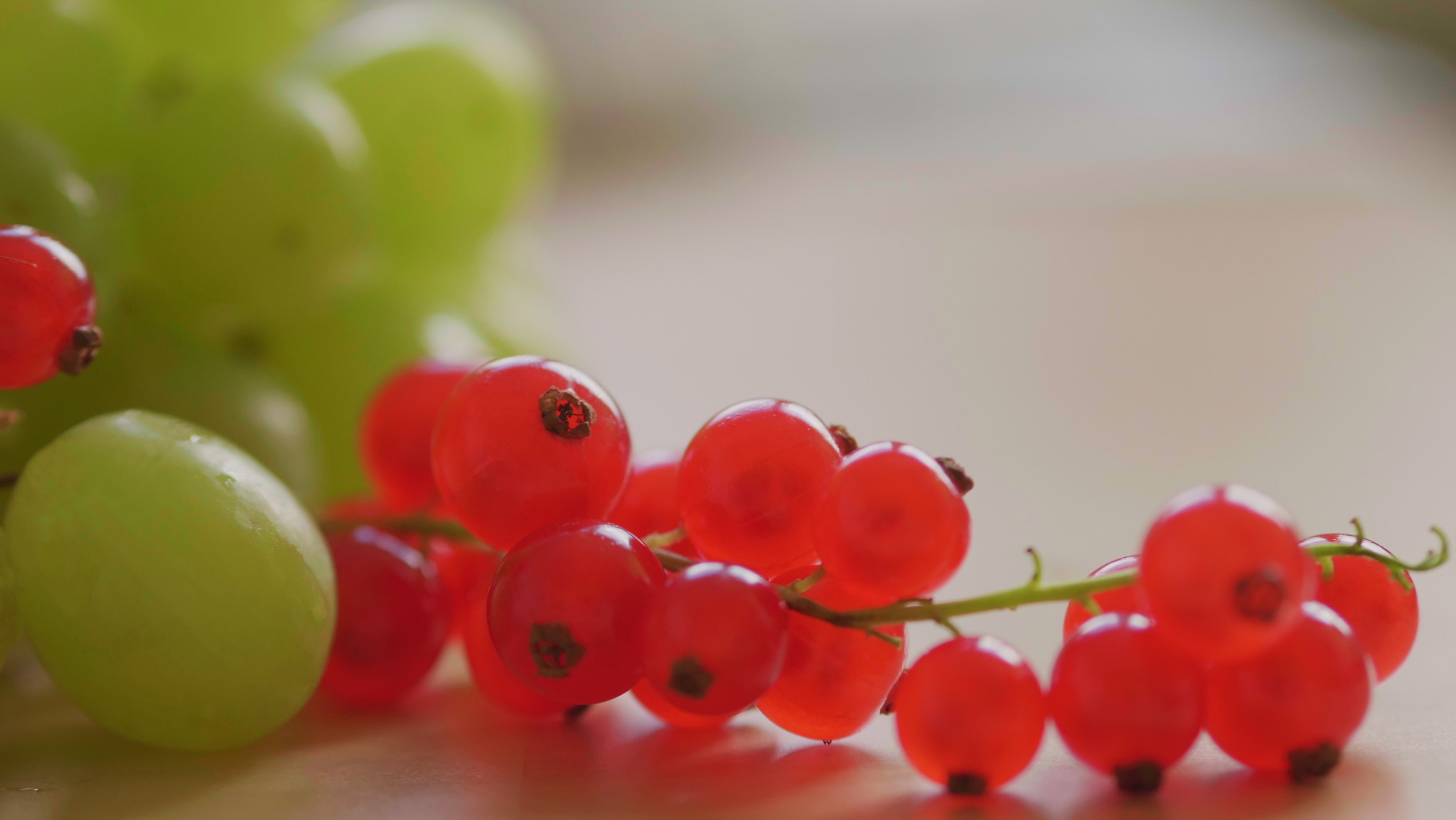 red currant berries and green grape on kitchen table at day, cop