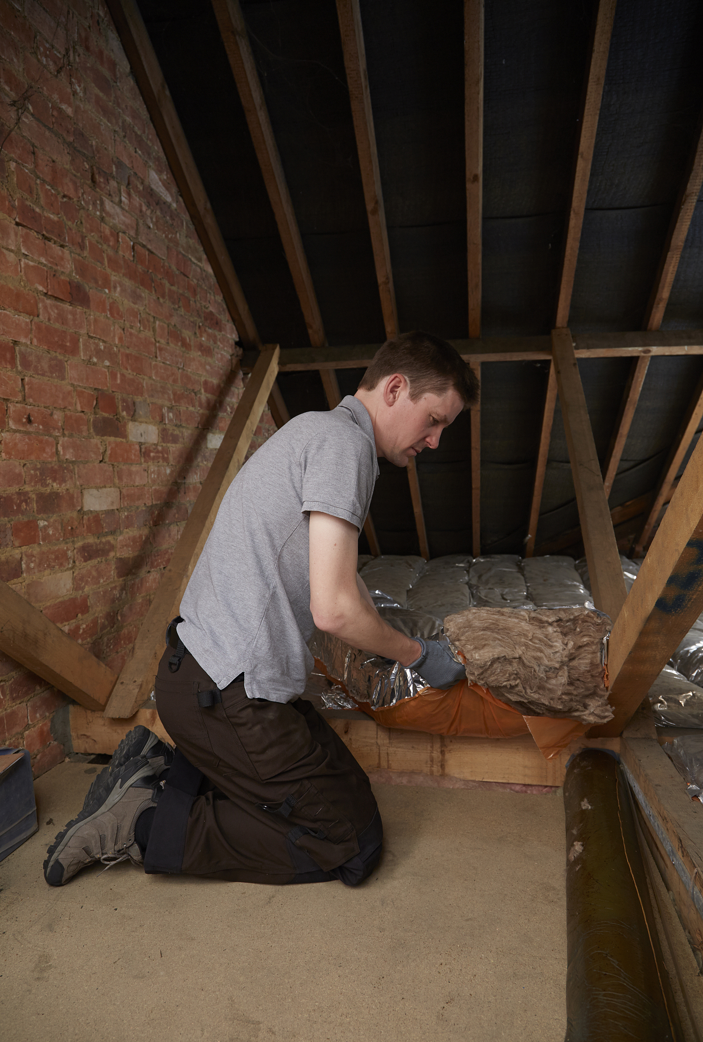 tradesman fits insulation in attic
