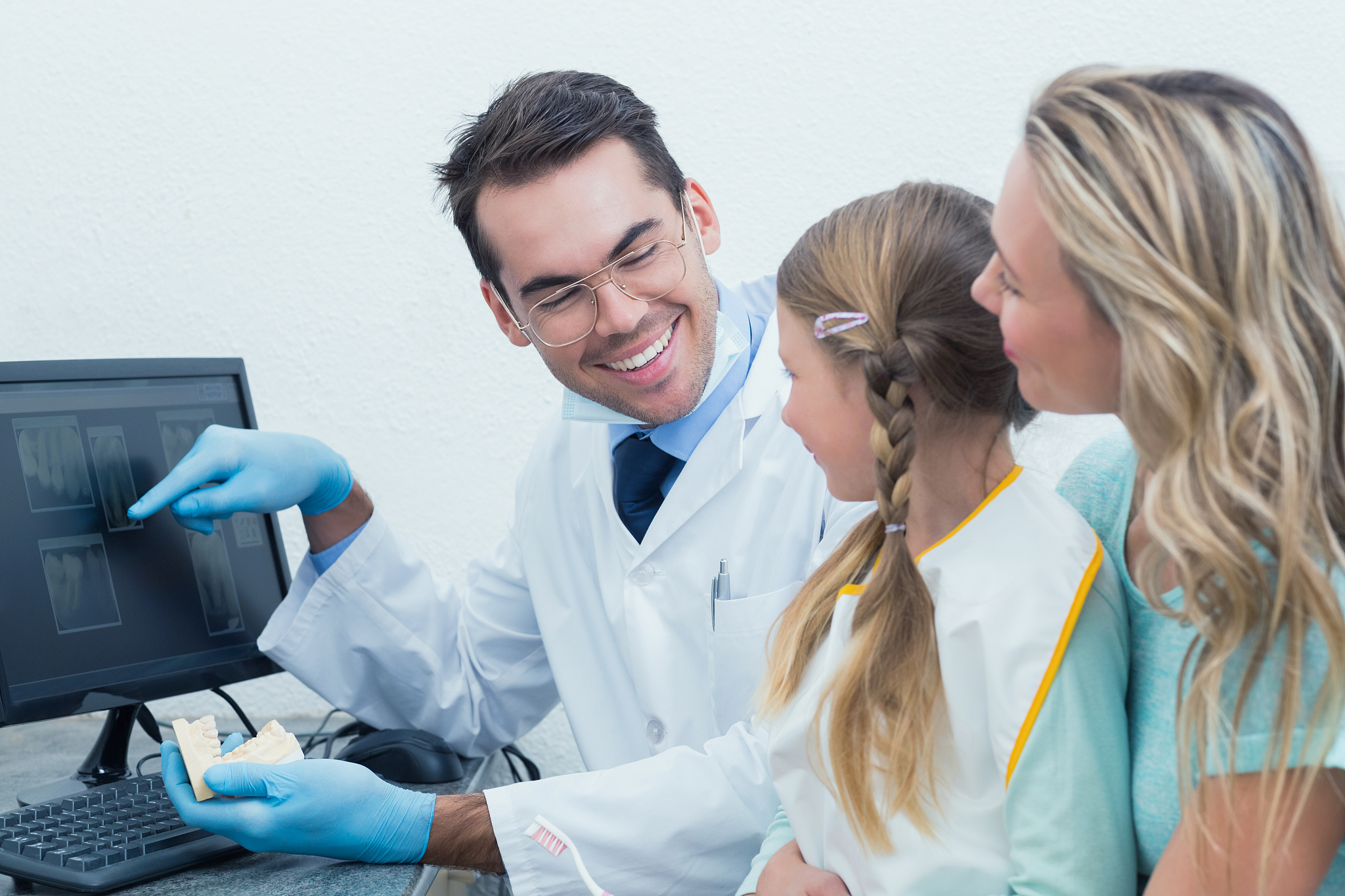 dentist with assistant showing little girl her mouth x-ray